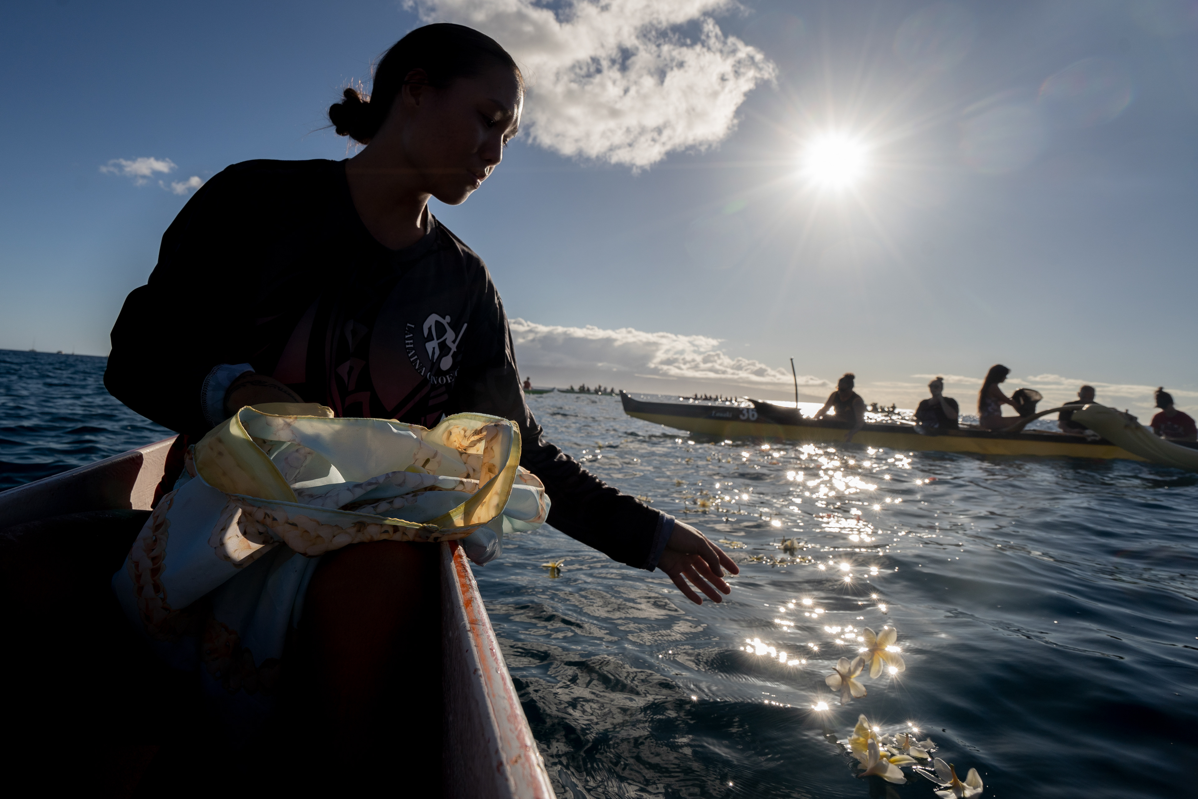 LAHAINA, HI - SEPTEMBER 8: Marley Calapini, a member of Lahaina Canoe Club, throws flowers in memory of her family members who died in the Lahaina Fire during a paddle out at Hanakaoo Park in Lahaina, Hawaii on September 8, 2023. (Photo by Mengshin Lin for The Washington Post)