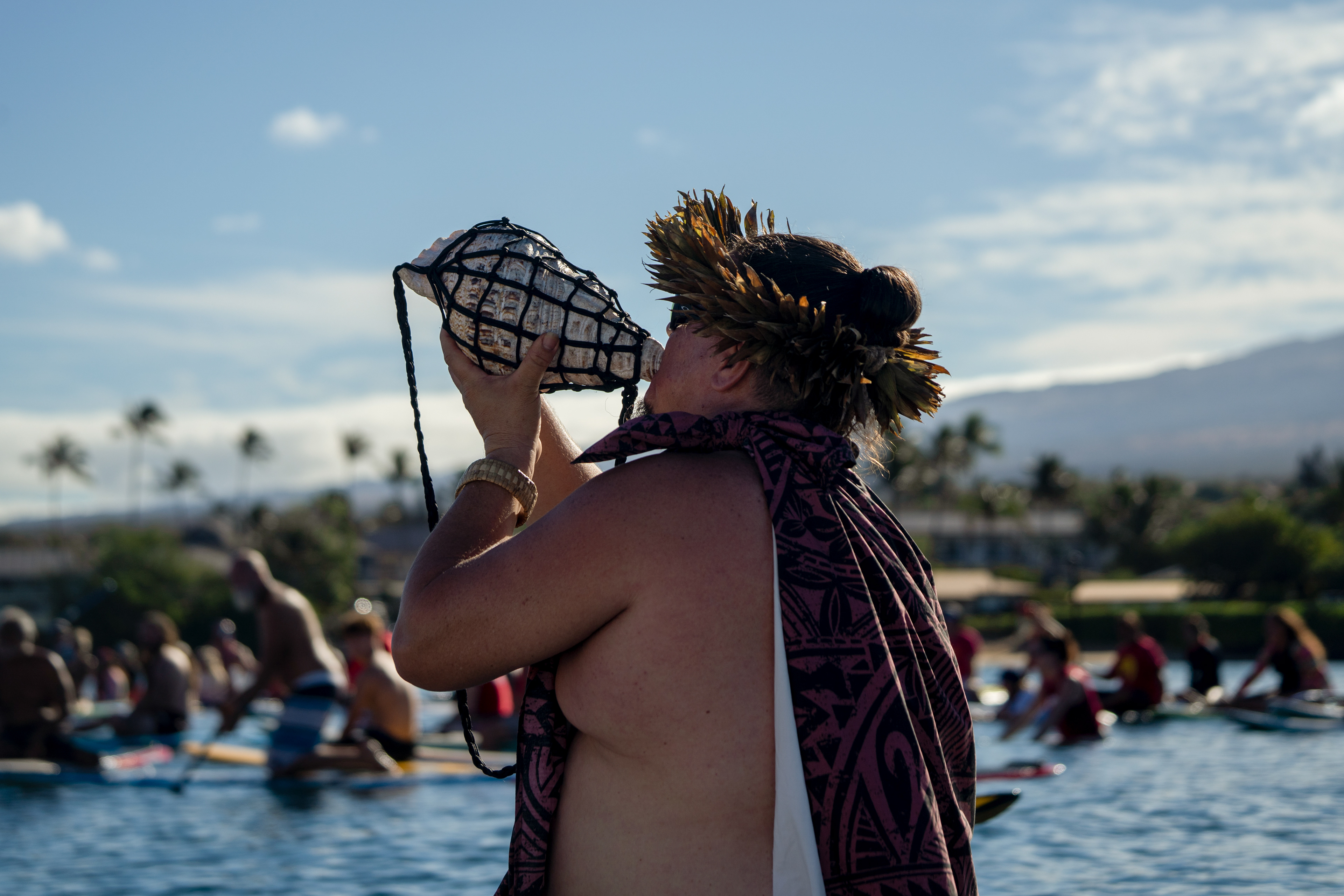 Kihei, HI - SEPTEMBER 8: Ua Aloha Maji blows a pu (conch shell) as dozens surfers paddling out at Kalama Beach Park in Kihei, Hawaii on September 8, 2023. (Photo by Mengshin Lin for The Washington Post)