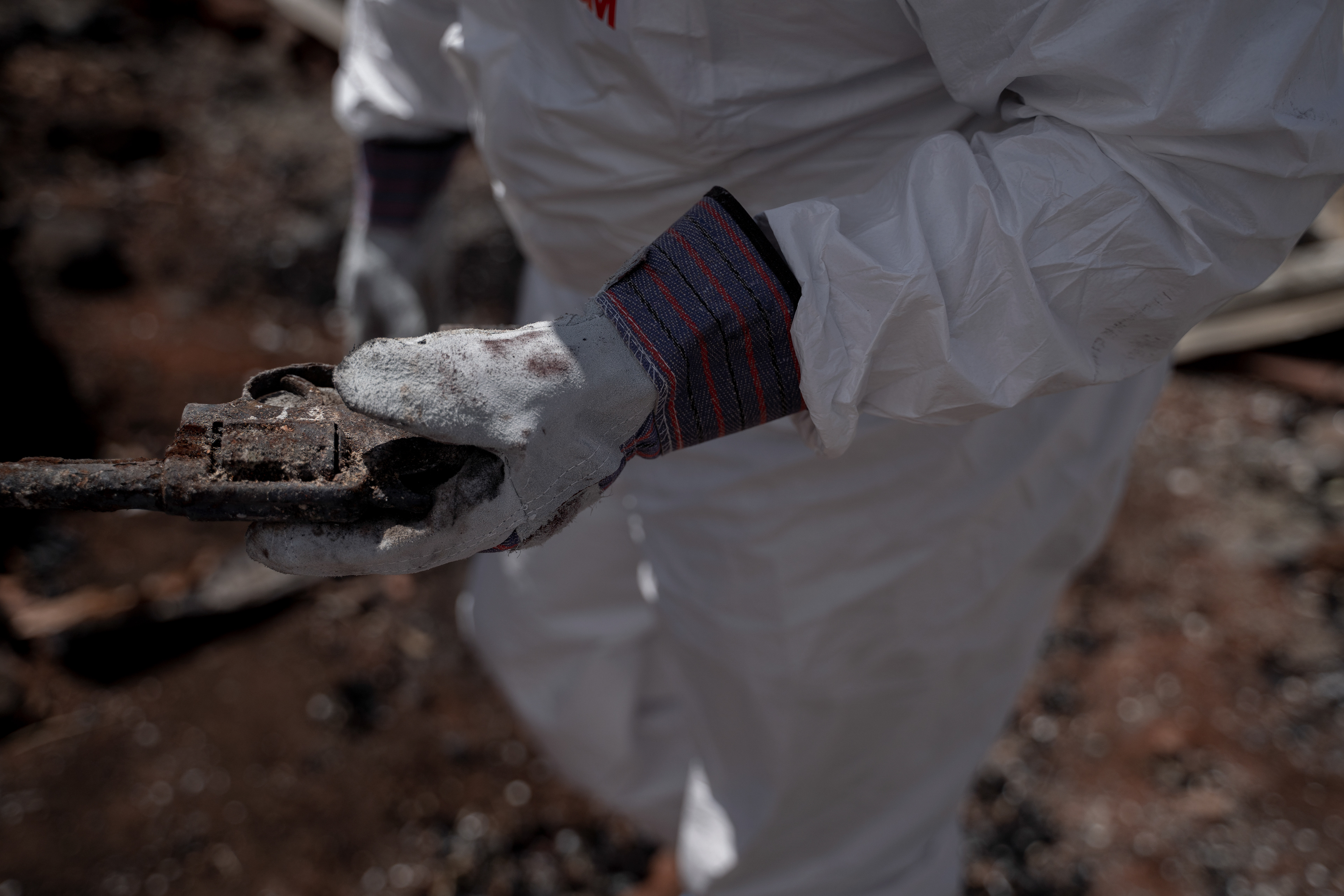 Michael Vera holds his grandfather’s pistol whom worked as a Maui police officer in Lahaina found in the rubble of their house on Tuesday, Sept. 26, 2023, in Lahaina, Hawaii. The Veras are among the couple dozens are able to return to their property in Zone 1-C. (AP Photo/Mengshin Lin)  