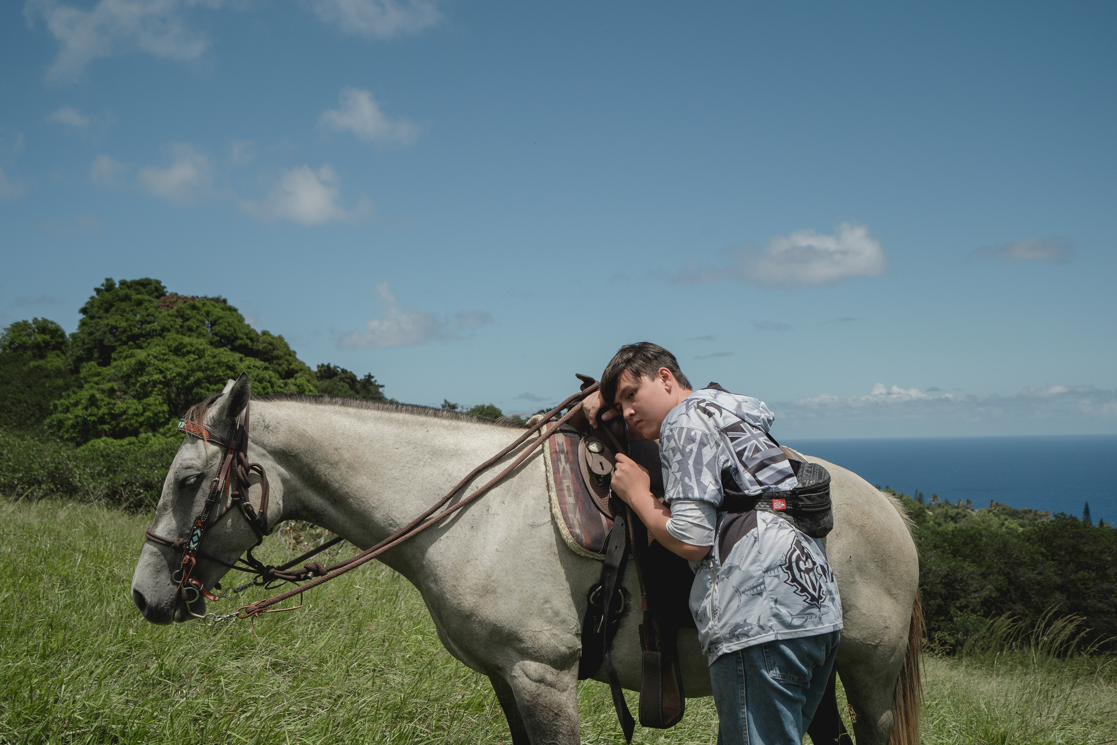 Hana, HI - AUGUST 24: Lucas Sequiera leans on his horse at Uakoko Ranch in Hana, Hawaii on August 24, 2023. (Photo by Mengshin Lin for The Washington Post)