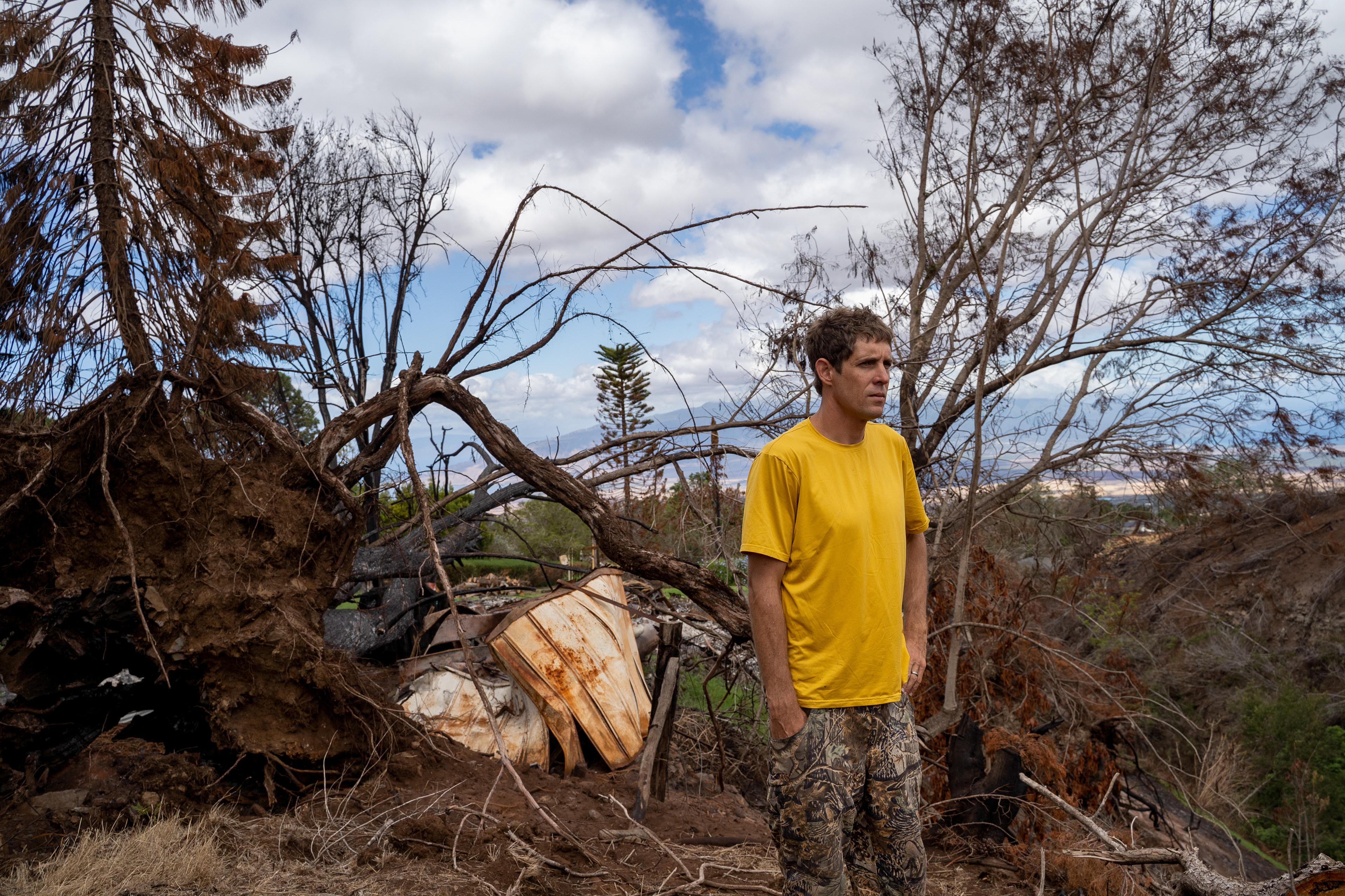 Kyle Ellison stands in front of a fallen tree on Wednesday, Sept. 27, 2023, in Kula, Hawaii. (AP Photo/Mengshin Lin)  