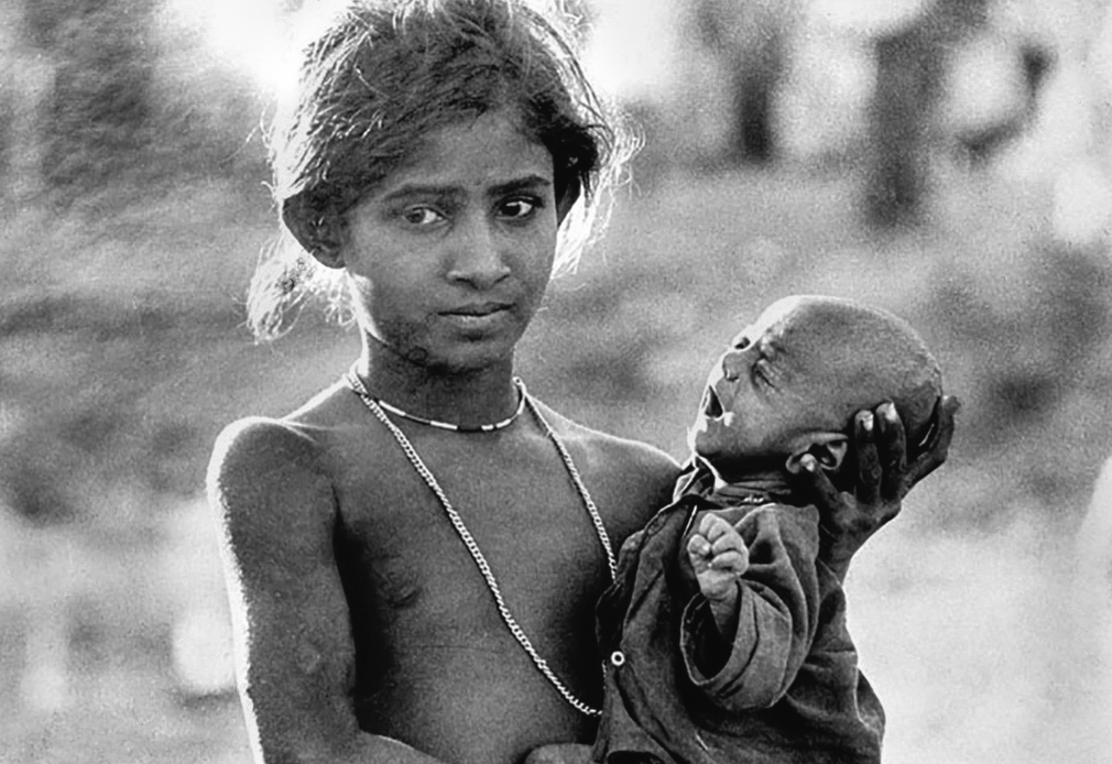 Krishanagar, West Bengal, India. 1970. A refugee child holds her newborn baby brother at a camp set up to accomodate refugees escaping from Pakistan,
