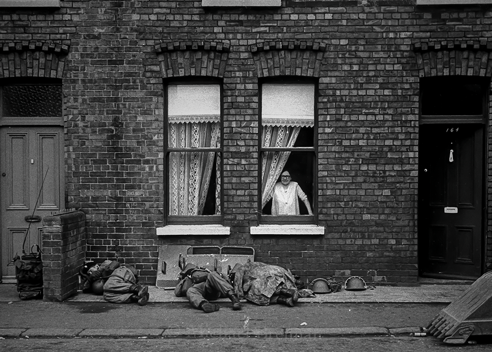 Belfast, Northern Ireland,. July 2,1970 An elderly resident of The Falls Road area looks from her front window to see British soldiers sleeping on the pavement. The soldiers had been imposing the curfew during the night.