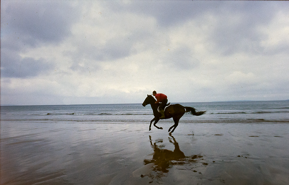 Ballybunion, Co.Kerry, Ireland. 1996. A rider runs his horse along the strand on a "soft day" at Ballybunion.