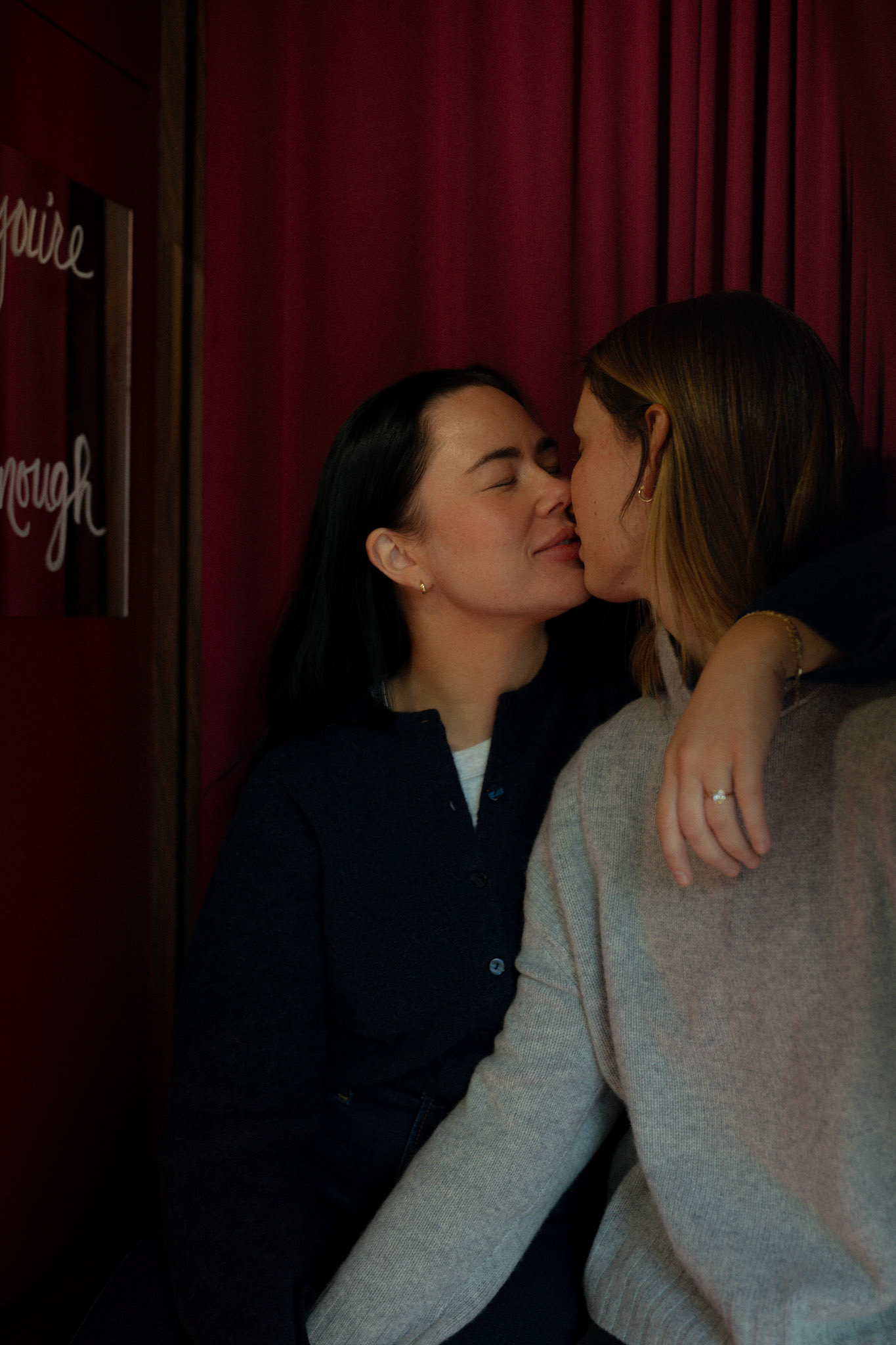Two women kiss in a photo booth.