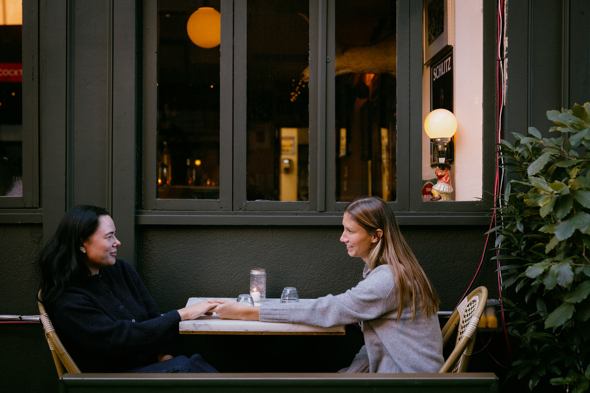 Couple holds hands across table at a West Village cafe.