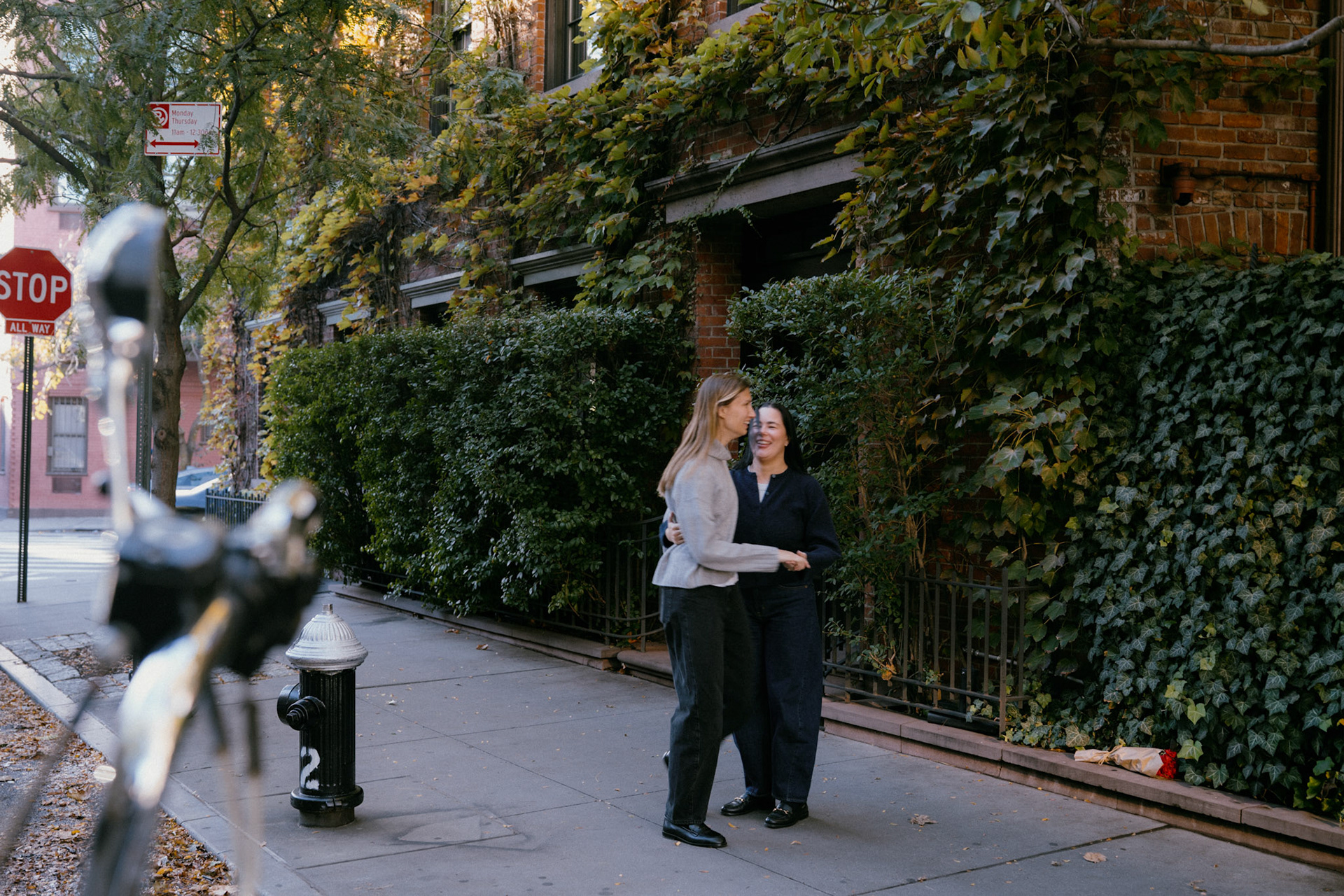 Couple holds each other and laughs in front of ivy covered brownstone in the West Village.