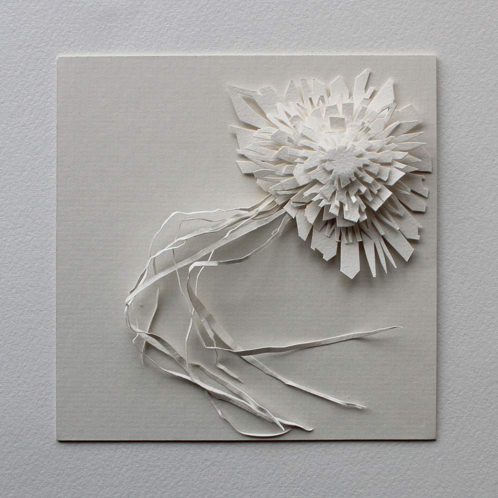 White paper sculpture with layers of hand cut paper in the top right corner, with strands of cut paper flowing down the canvas.
