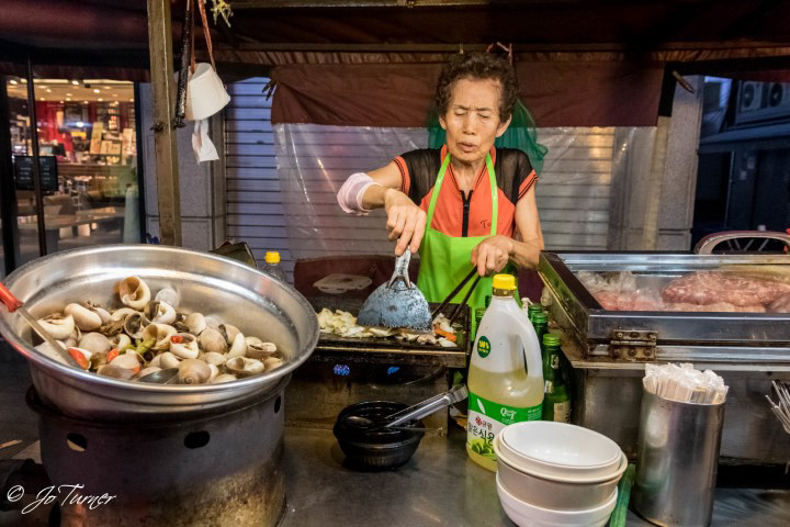 Kim Il-sun prepares dalkgalbe — spicy chicken with vegetables, stir-fried in soju — at Auntie's Soju Tent