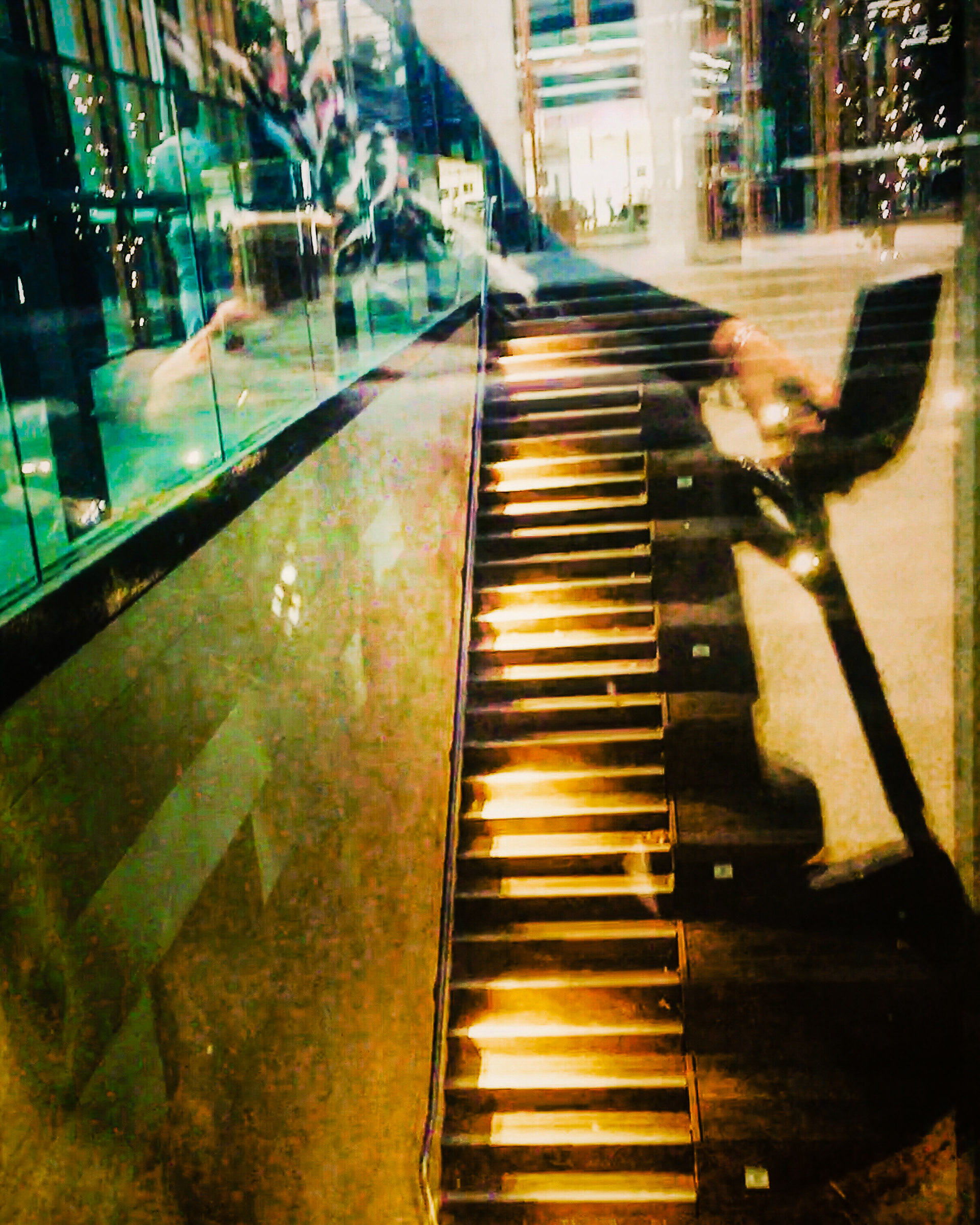 Bronze stairs behind a glass panel, reflecting Karen's wheelchair