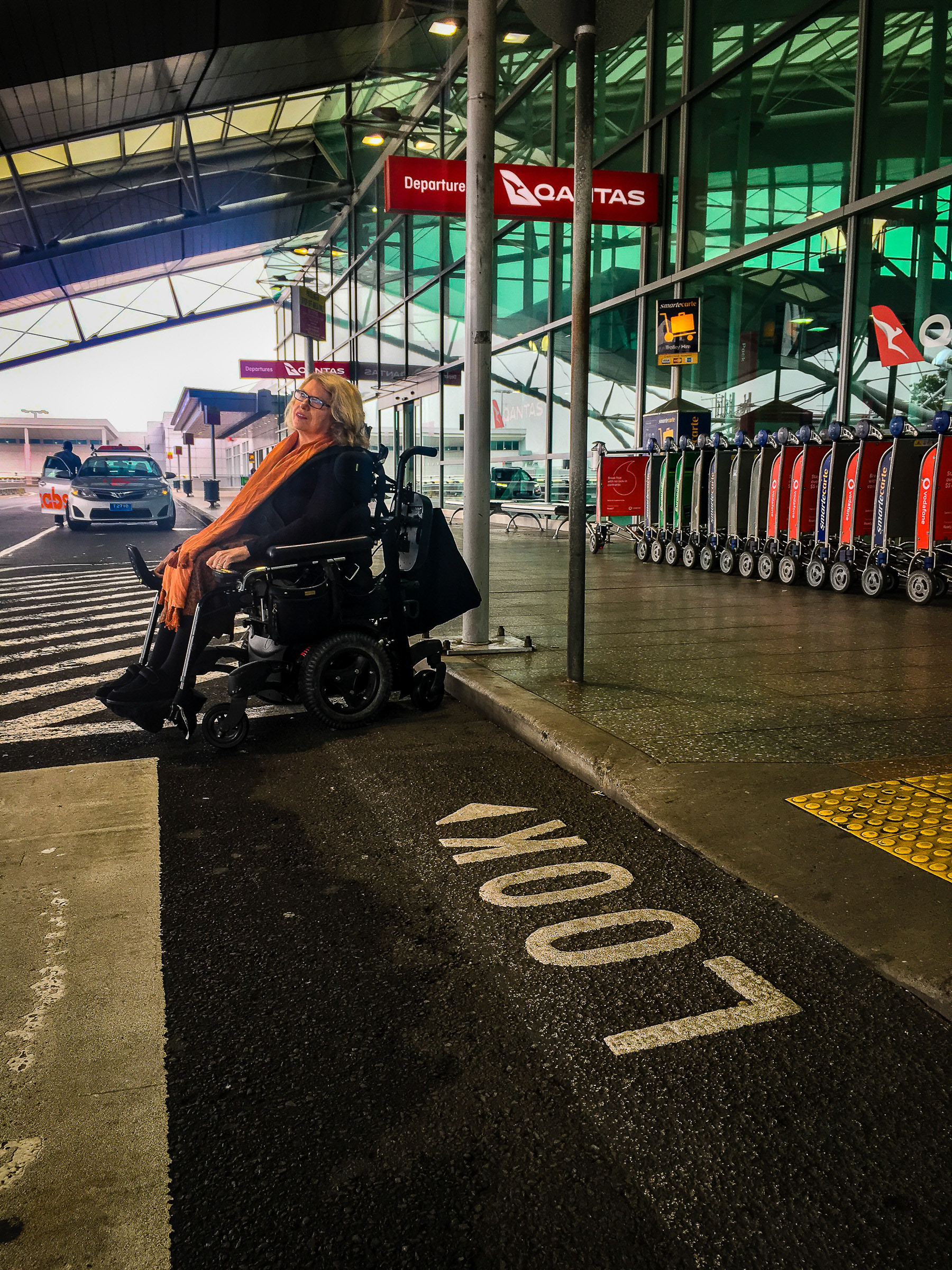 Karen at Sydney airport sitting in her wheelchair next to the words LOOK on the ground