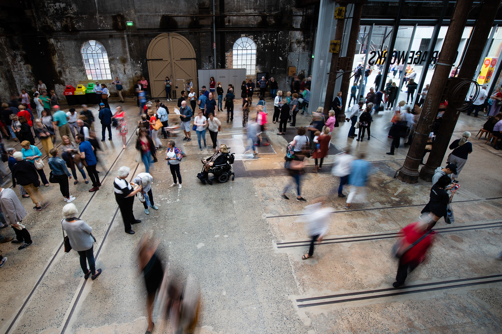 Karen, alone and still in her wheelchair in a crowded space, with movement all around her