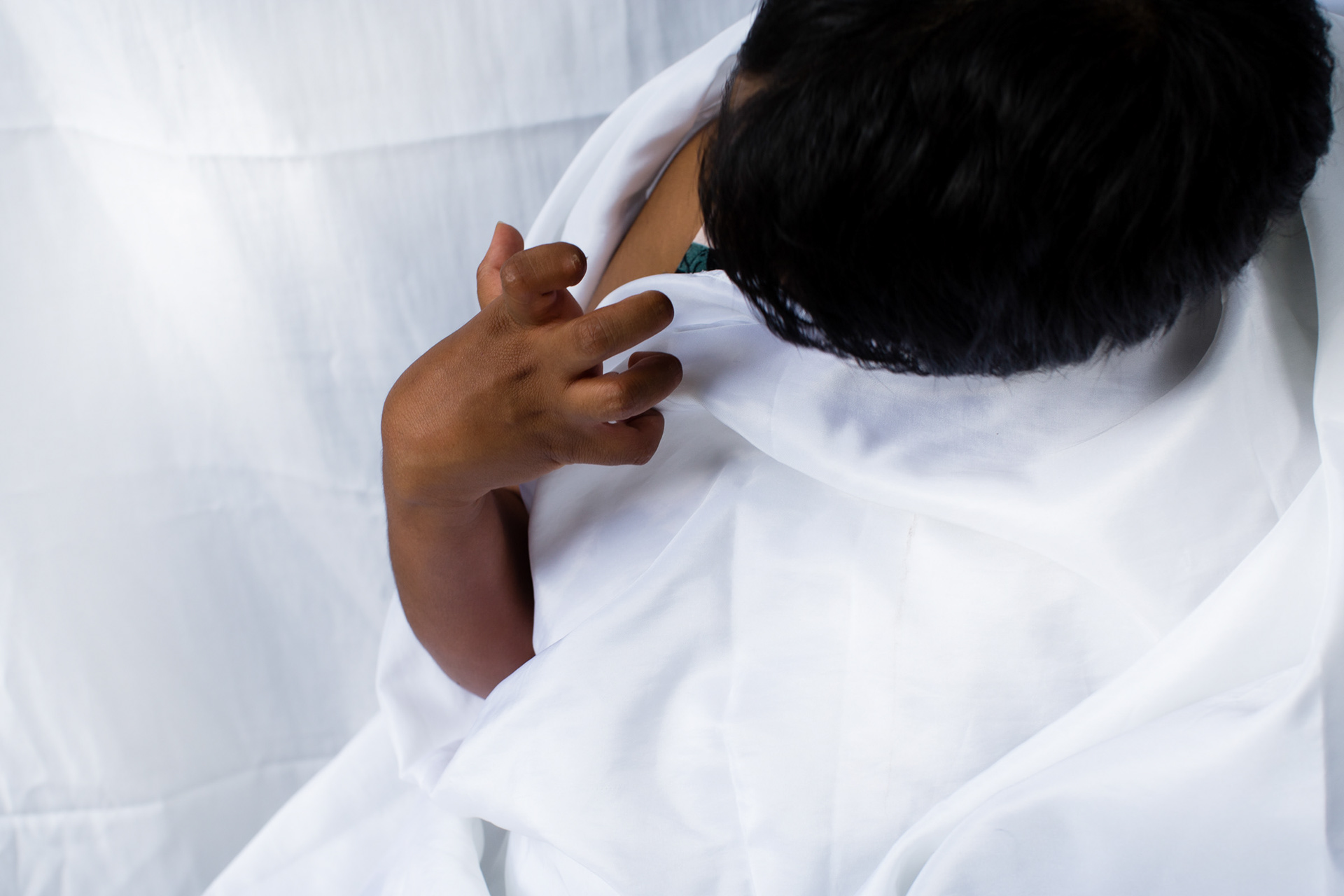 Marusha looking at her clunched fingers against a white backdrop