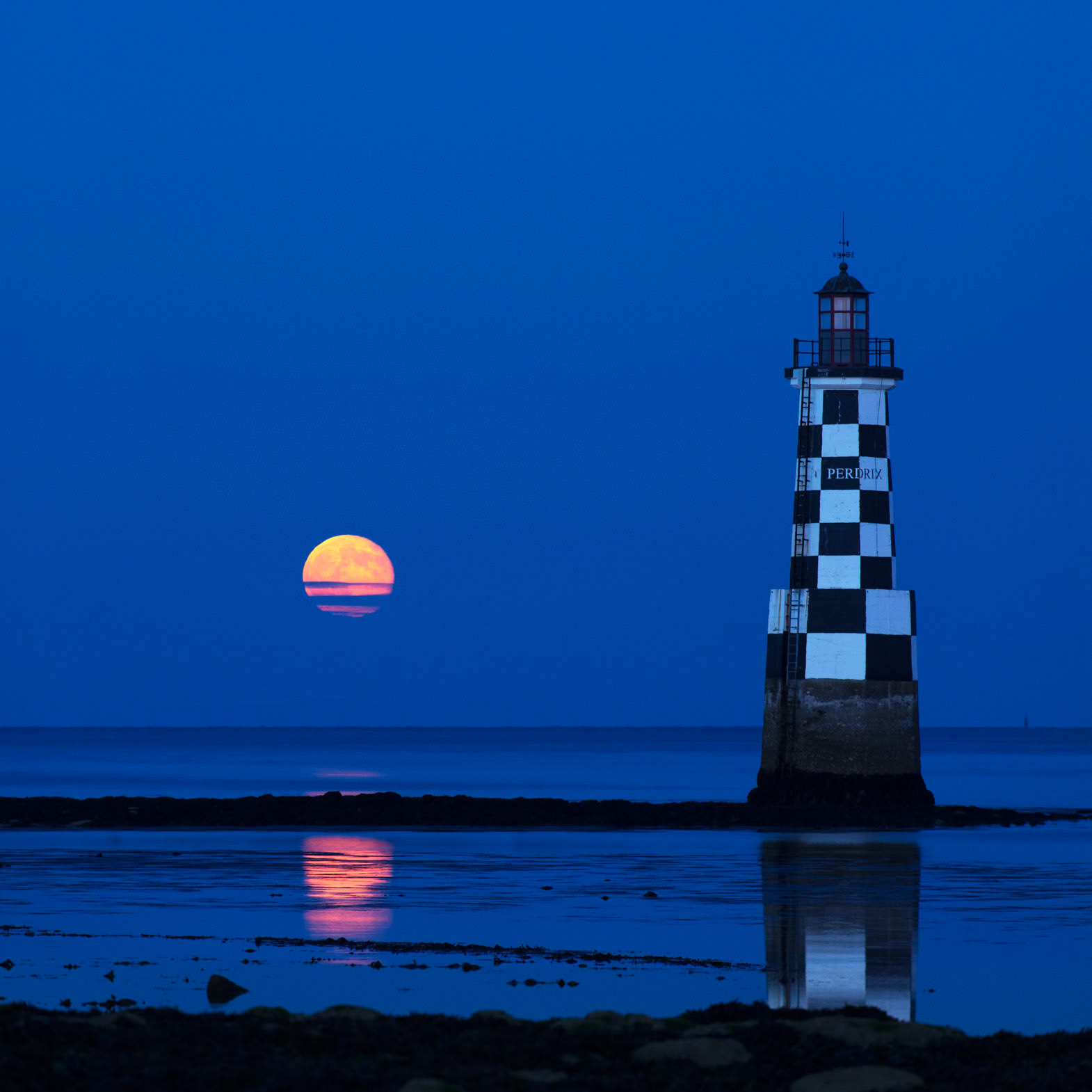 La Super Lune (la plus grosse de l'année 2013) émerge des nuages en se levant à gauche du phare de la Perdrix à l'ïle-Tudy (en Finistère) et son célèbre damier. EXIF : Canon 6D + Sigma 100-300 f/4.0 à 300 mm et f/8.0. 0,6 s à 1600 ISO. 22h10