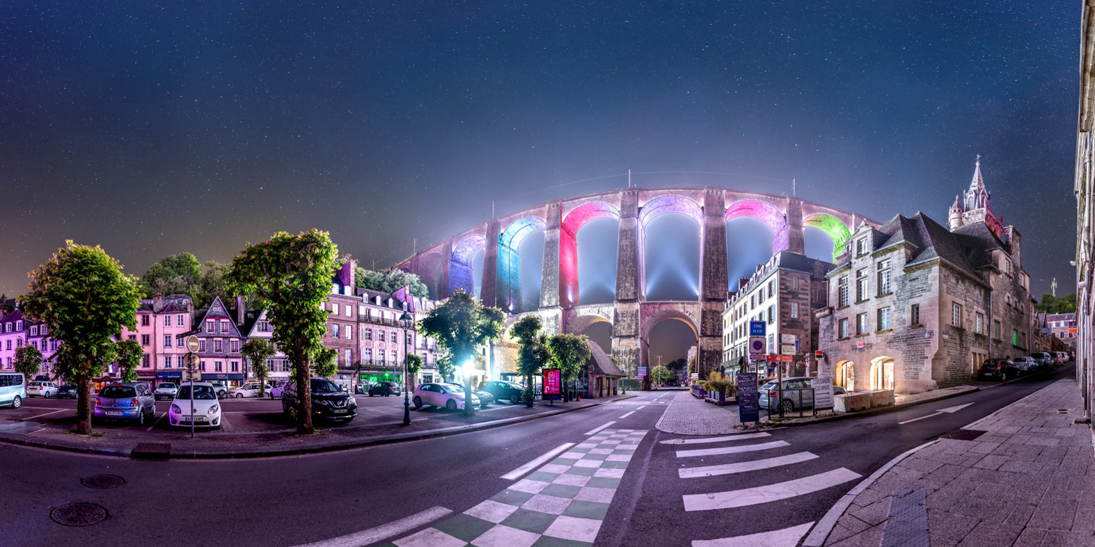 En ce début juin, les lumières de la ville sont éteintes, mais le viaduc et la mairie restent éclairés par des spots de couleur. Sous cet angle, près de l'église Saint-Mélaine, les arches du viaduc sont défformées par la projection du panorama.