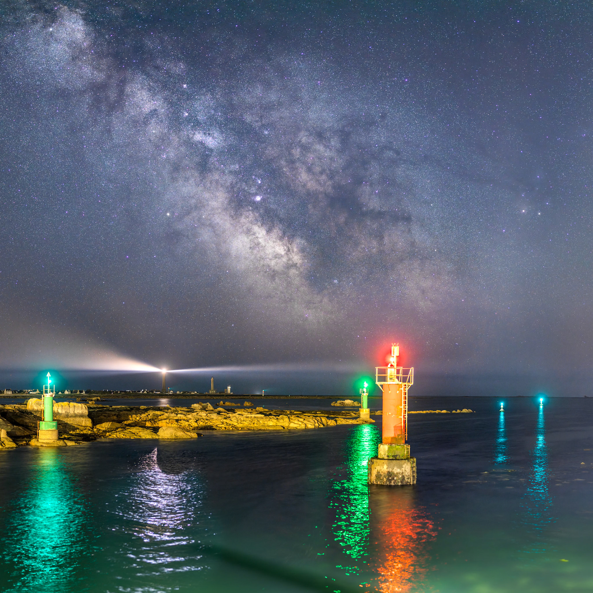 Depuis l'extrêmité du port de saint-Gunéolé, je fais face au sud où la Voie lactée forme un incroyable arrière-plan, avec au premier plan les nombreuses balises qui jalonnent le chenal d'accès au port, et plus loin, les phares de Penmarc'h et le sémaphore.