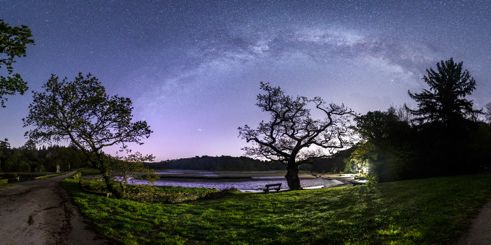 Un très beau chêne se dresse sur le site de saint-Maurice aux bords de la Laïta. La Voie lactée déploie son arche dans le firmament. Par chance, la façade de la crêperie Saint-Maurice (tout à droite) est illuminée et cette lumière apporte du contraste. Le Quartier de Lune, qui est bas sur la gauche, éclaire aussi la végétation. Quelques traces chaudes de pollution limeuse réchauffent l'horizon.