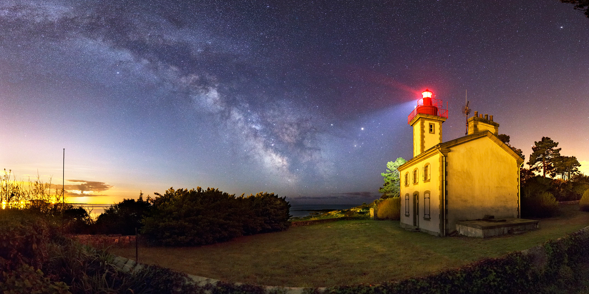 Le Quartier de Lune vient de se lever et est maintenant derrière le nuage en bas à gauche. Sa lumière teinte le ciel en bleu où s'épanouit la Voie lactée devant le feu de Combrit.