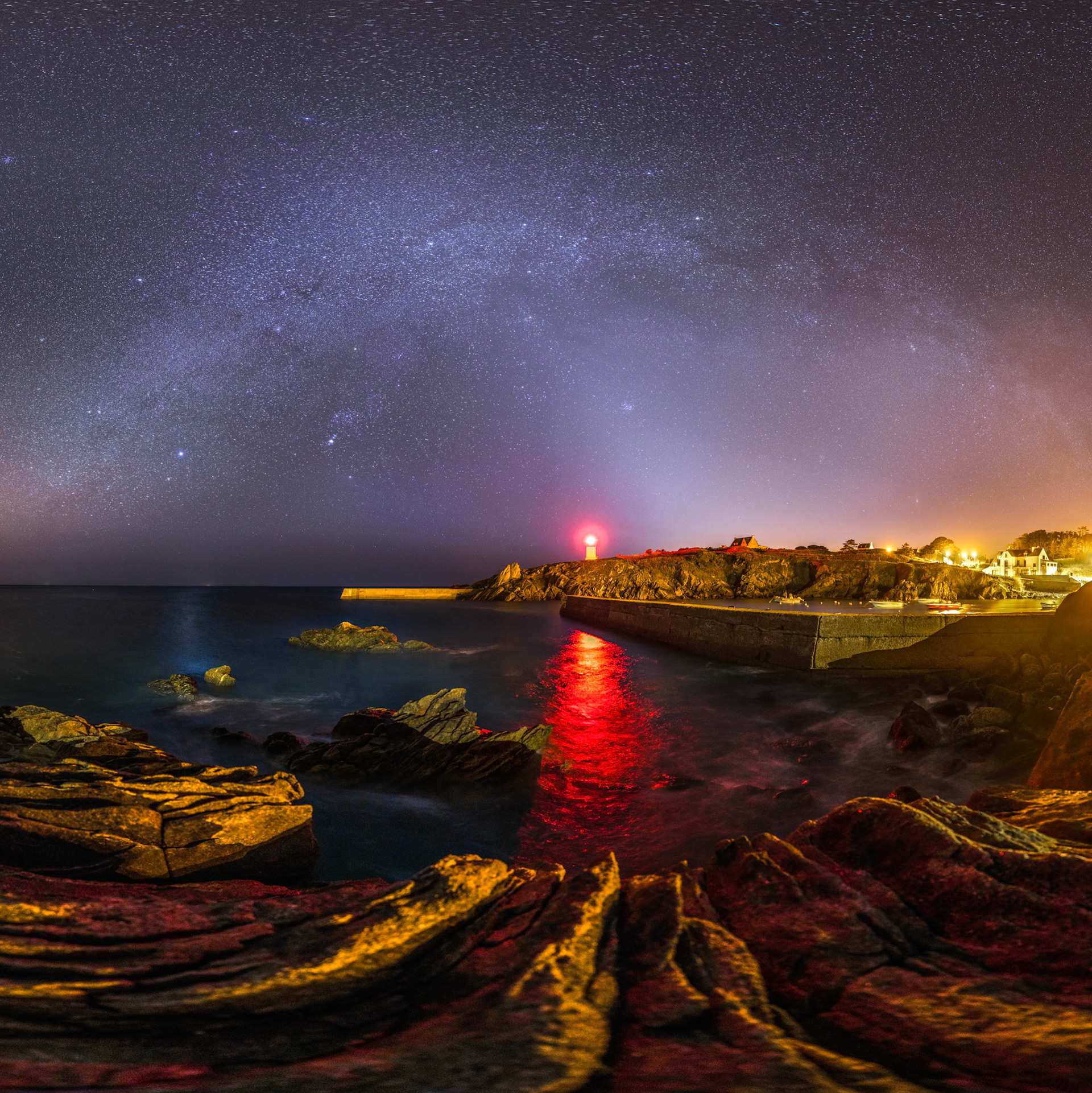 La nuit tombe sur Pors Poulhan. La voie lactée d'hiver étend sa large et pâle arche piquée de millions d'étoiles au-dessus du petit port de Plouhinec. Le Feu de Pors Poulhan brille d'un éclat rouge puissant. Plus à gauche, le reflet bleuté de l'étoile Sirius. Les rochers sont d'un orange marqué à cause de tous les lampadaires qui illumine le port. Une langue de lumière très pâle s'étend en diagonale au-dessus du feu. Il s'agit de la lumière zodiacale (des poussières dans le plan du Système solaire éclairées par le Soleil).