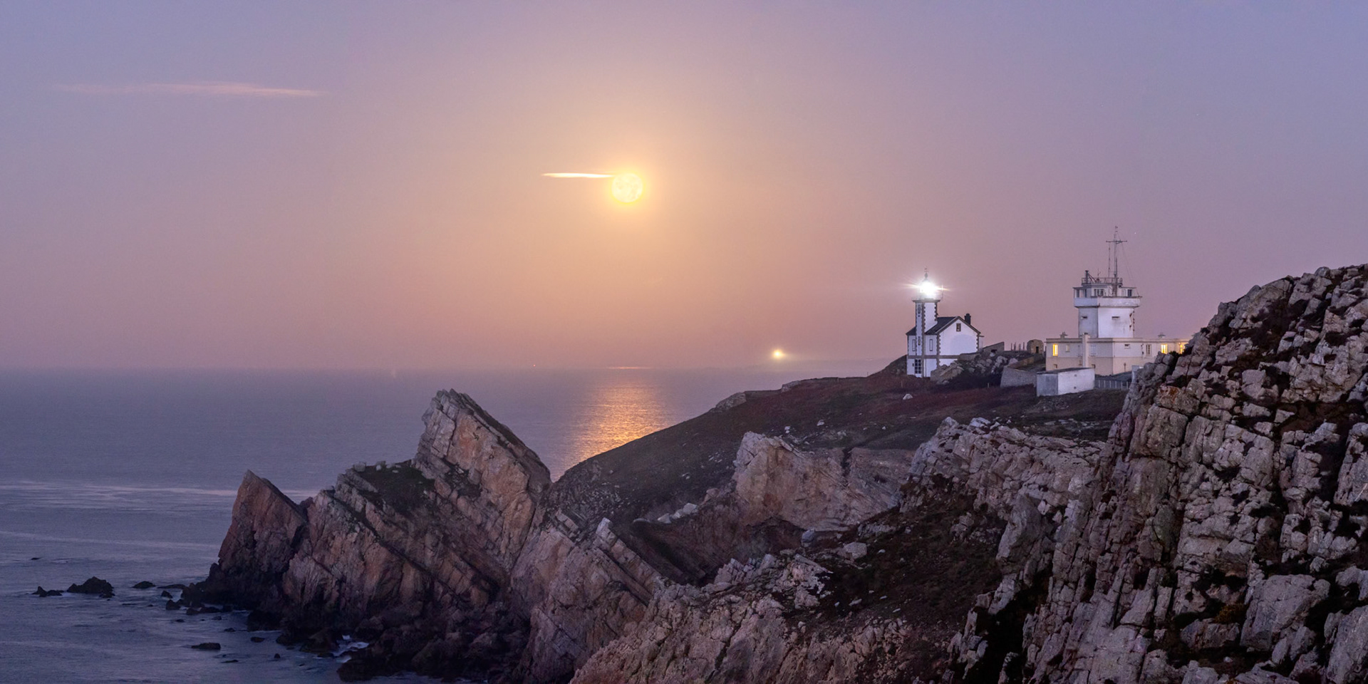 La Pleine Lune se couche à gauche du phare du Toulinguet (à 500 m de là), non loin de la lointaine lumière du phare de la Pointe Saint-Mathieu (à 12 km) à Plougonvelin. A droite du phare, l'imposant sémaphore du Toulinguet.