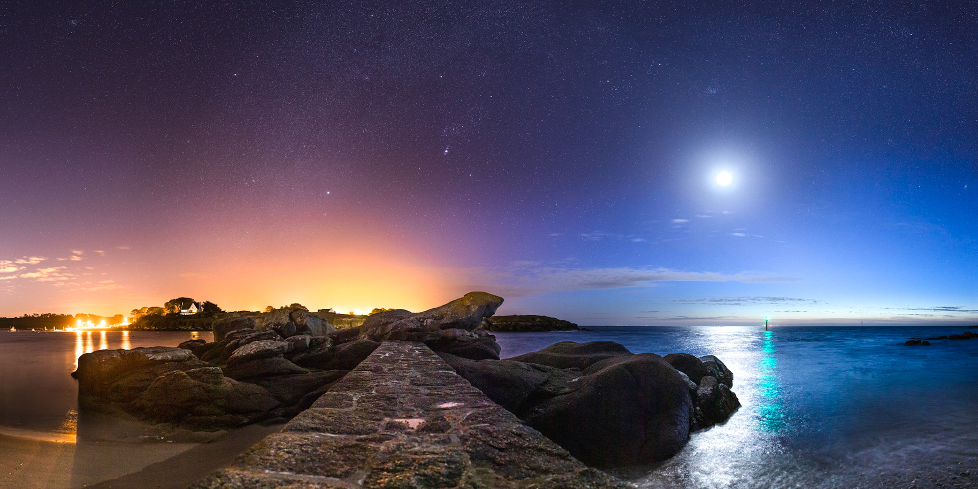 Le Rocher du Crapaud, situé à l'embouchure nord de l'Aber Ildut, sur la commune de Lanildut, auquel mène une digue. Les teintes bleues du crépuscule et du Croissant de Lune (à droite) contre-balancent à merveille les teintes oranges de la pollution lumineuse (à gauche). Une balise verte tout à droite complète la gamme de couleurs.