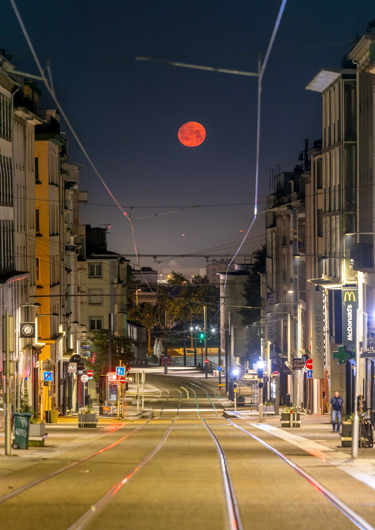 La Pleine Lune de juin est baptisée "Lune des Fraises" dans le folklore américain. Ce 10 juin 2025, elle porte bien son nom car les méga-feux qui ravagent une partie des forêts du Canada émettent des cendres qui circulent dans la haute atmosphère et se trouvent ce matin (il est 4h45) entre la Pleine Lune et moi. En diffusant la lumière bleue, ces cendres provoquent un assombrissement de la Lune (elle devrait être sensiblement plus lumineuse alors qu'elle est à 1,6° au-dessus de l'horizon)  mais surtout rendent l'astre bien plus orange qu'il ne devrait l'être en temps normal. Ainsi, la Lune d'un orange profond se rapproche de la couleur des fraises. A l'aide de l'application PhotoPills, j'avais anticipé quà cette heure-ci, la Lune serait pile dnas l'axe de la Rue Jean Jaurès, à la verticale du phare du Portzic dont on perçoit à peine trois points lumineux serrés.