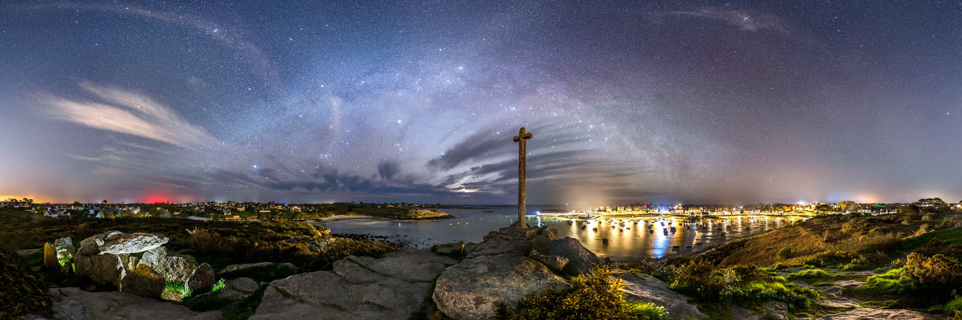 Les conditions ne sauraient être plus idéales. Le port de Portsall apporte une bonne dose de chaleur à droite, tandis que la présence de la Lune partiellement masquée par les nuages, rafraichit le ciel d'une discrète teinte bleue. Tout à gauche, la présence de Brest teinte des cirrus à la verticale d'éoliennes rouges proches de Plougonvelin. Pour révéler l'allée couverte de Guilliguy, je l'ai éclairée par le flash de mon smartphone posé en deux endroits.