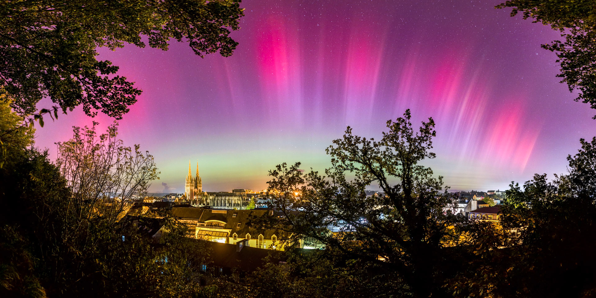 J'avais pris le pari que les aurores boréales seraient si intenses cette nuit du 10 octobre 2024 qu'elles seraient visible au-dessus de Quimper. La tempête solaire se réactive subitement et de fines streuctures aux couleurs dégradées, presque irréelles, se forment. La vue depuis le Mont Frugy est idéale avec ce cadre naturel formé d'arbres et l'arbre à droite du centre qui remplit bien une zone du ciel plutôt vide. Avec la cathédrale Saint-Corentin en fond, il est facile de reconnaître le lieu.
