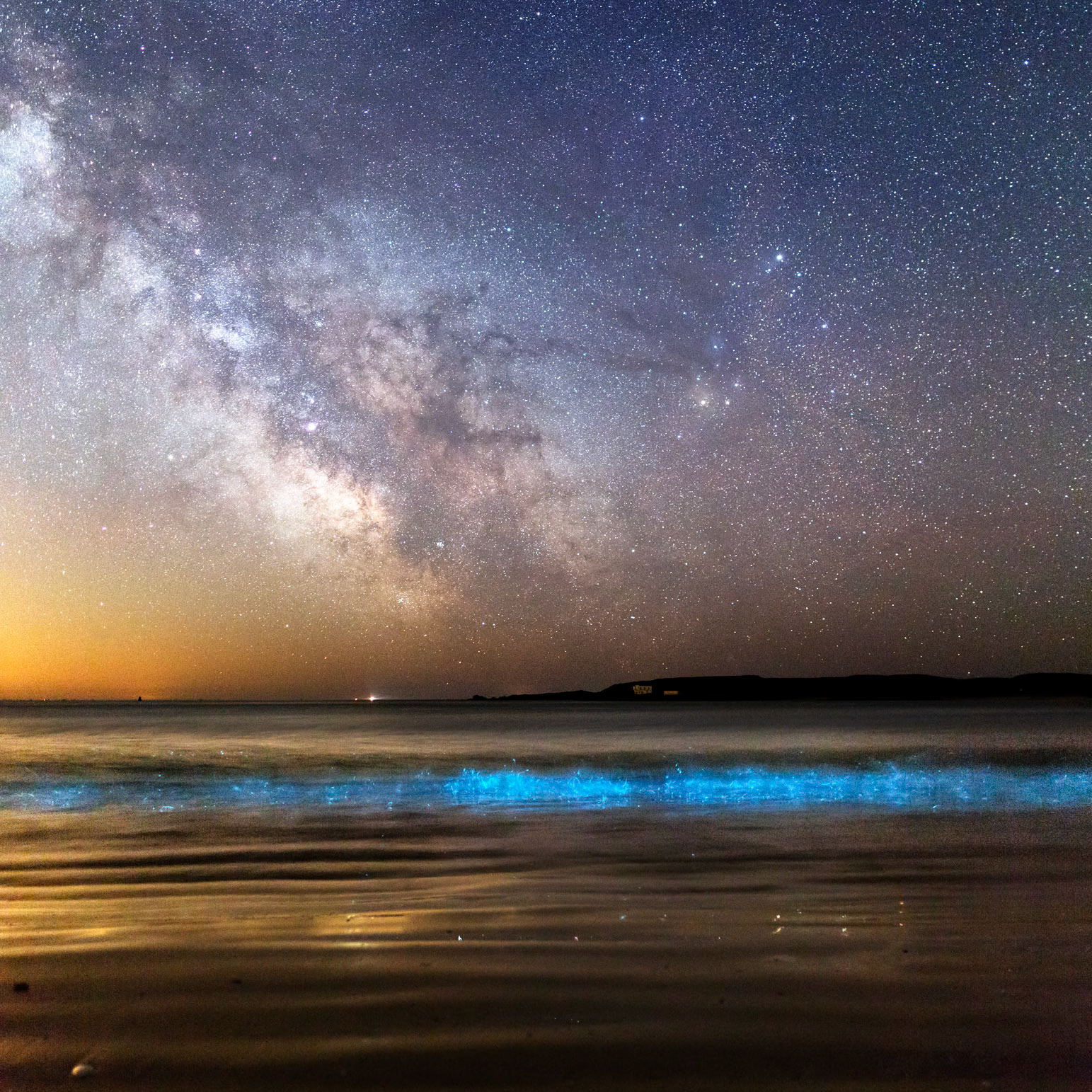 Les rouleaux qui se brisent sur la plage de Tréac'h er Goured sont illuminés par la présence de plancton phosphorescent. Dans le ciel, la Voie lactée située entre le Scorpion et le Sagittaire est magnifique.