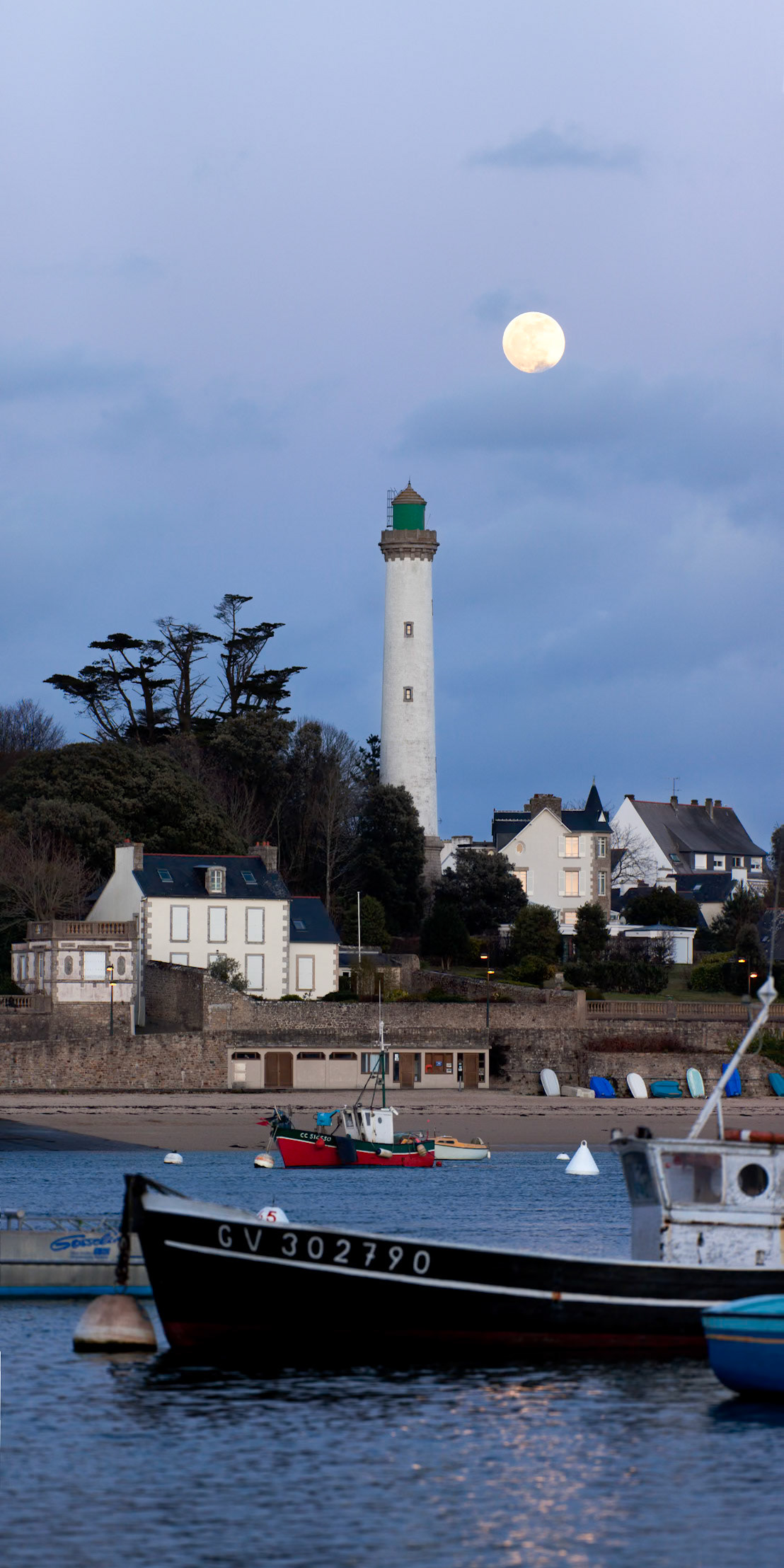 La Pleine Lune émerge de derrière les nuages et montre son disque bien rond aux côtés du phare de Bénodet.