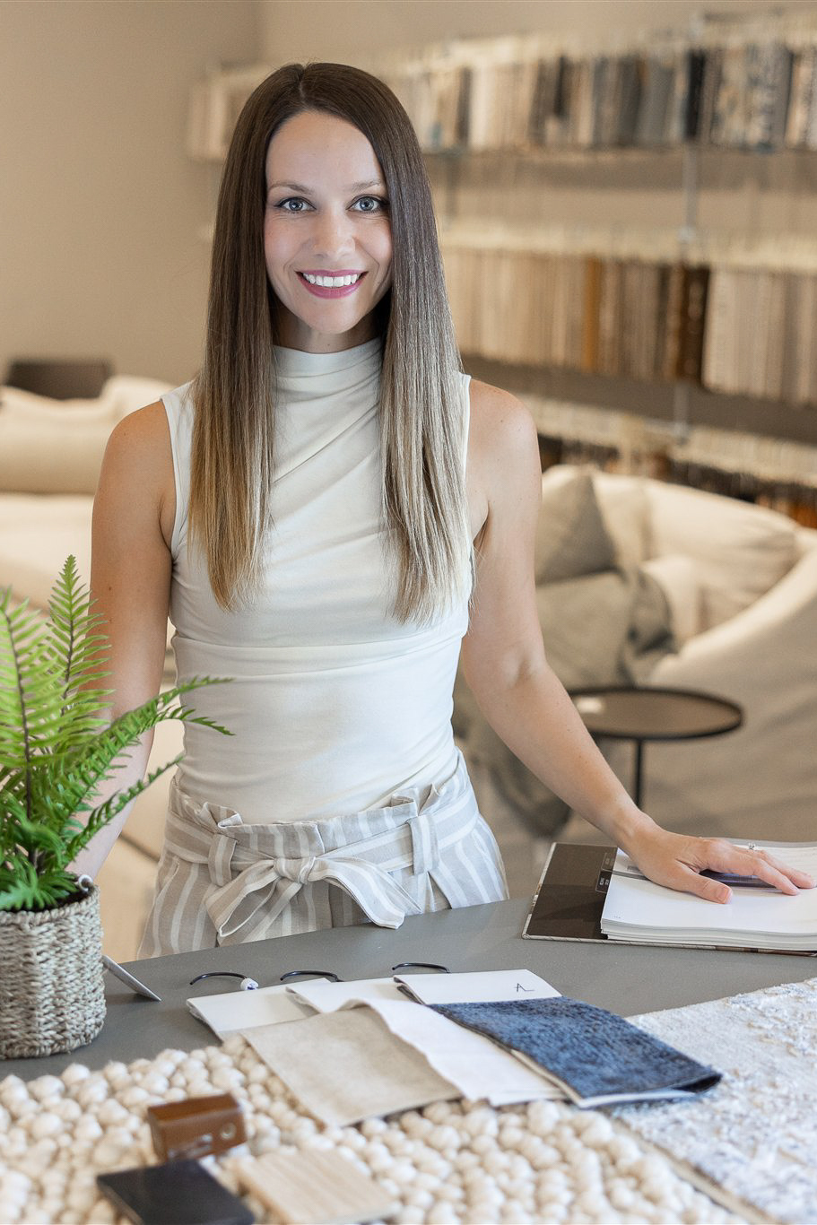 Interior designer Elizabeth Brown standing at a studio desk with fabric swatches and floor plans, illustrating the professional design process for Panama City and Emerald Coast homeowners.