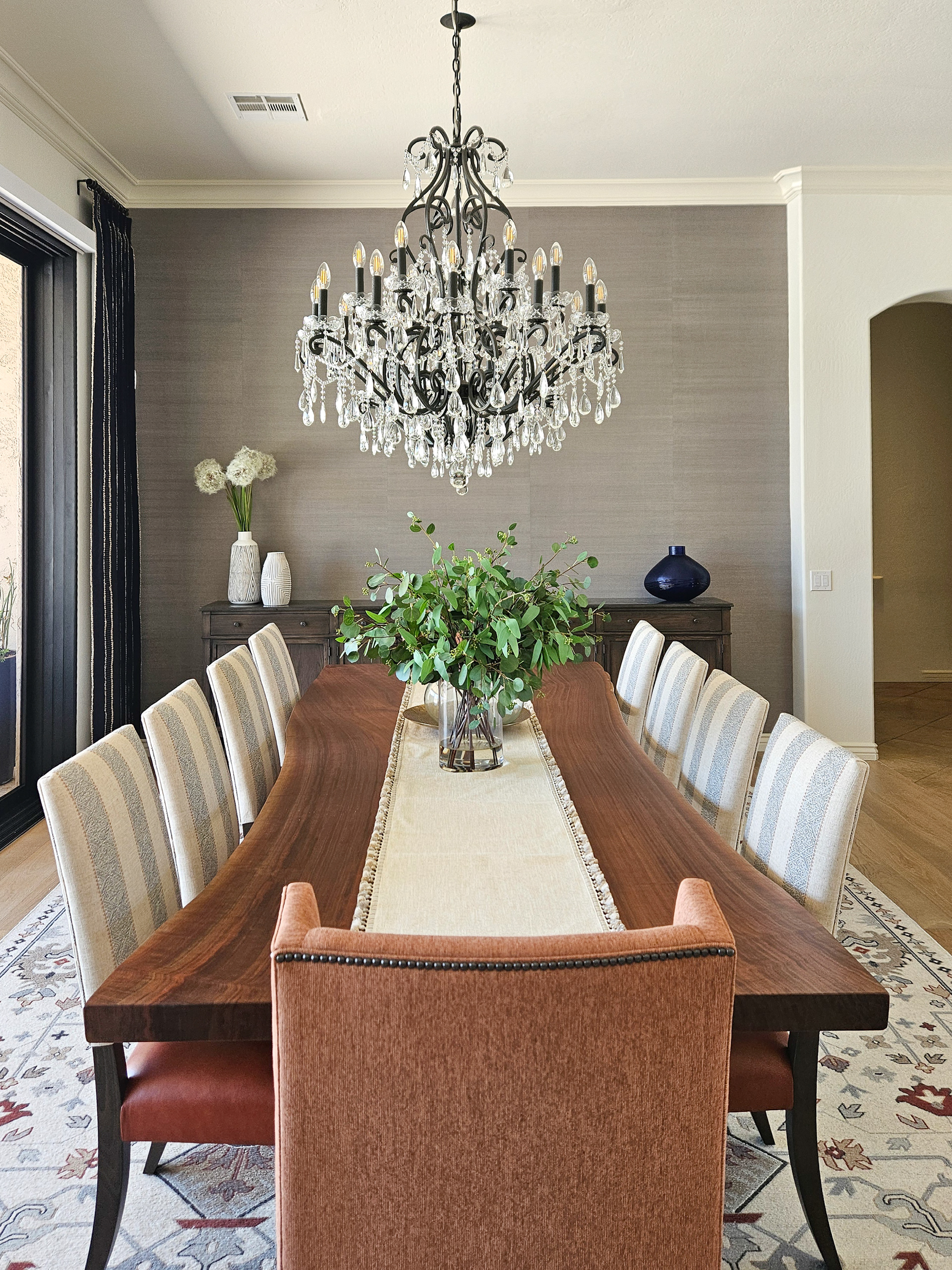 A symphony of scale where the brilliance of crystal chandeliers meets the raw, organic edge of a live edge dining table.