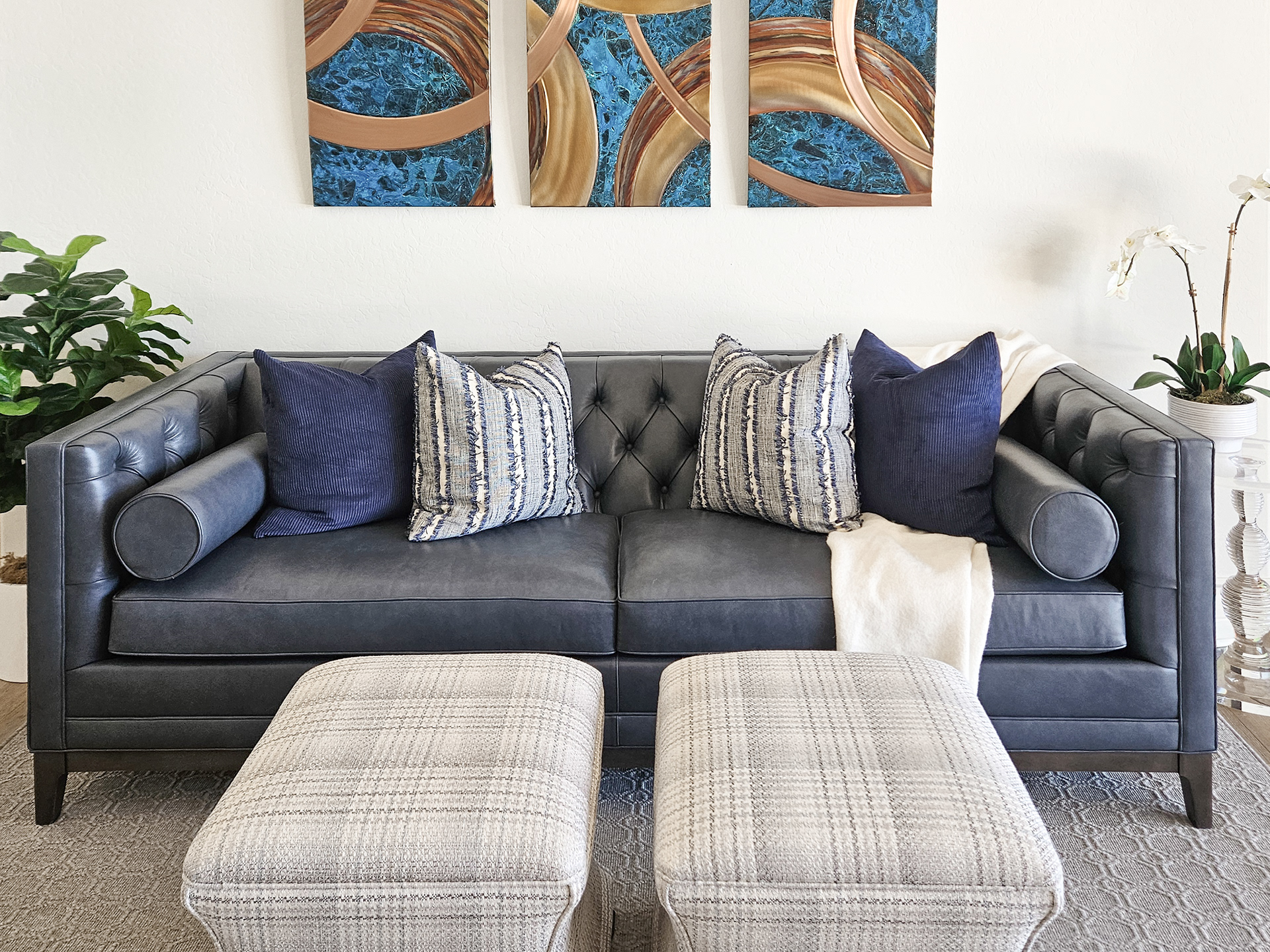 The weighted structure of deep slate blue leather is softened by woven textiles and the rhythmic flow of curated abstract art.