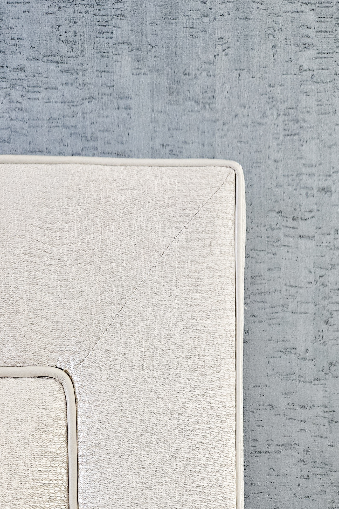 The intersection of refined welted leather and the organic, metallic grain of a textured wallcovering.