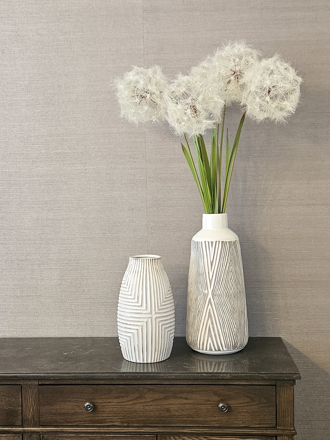 A study in geometric repetition and organic line work, where etched ceramics meet the tactile depth of natural grasscloth.