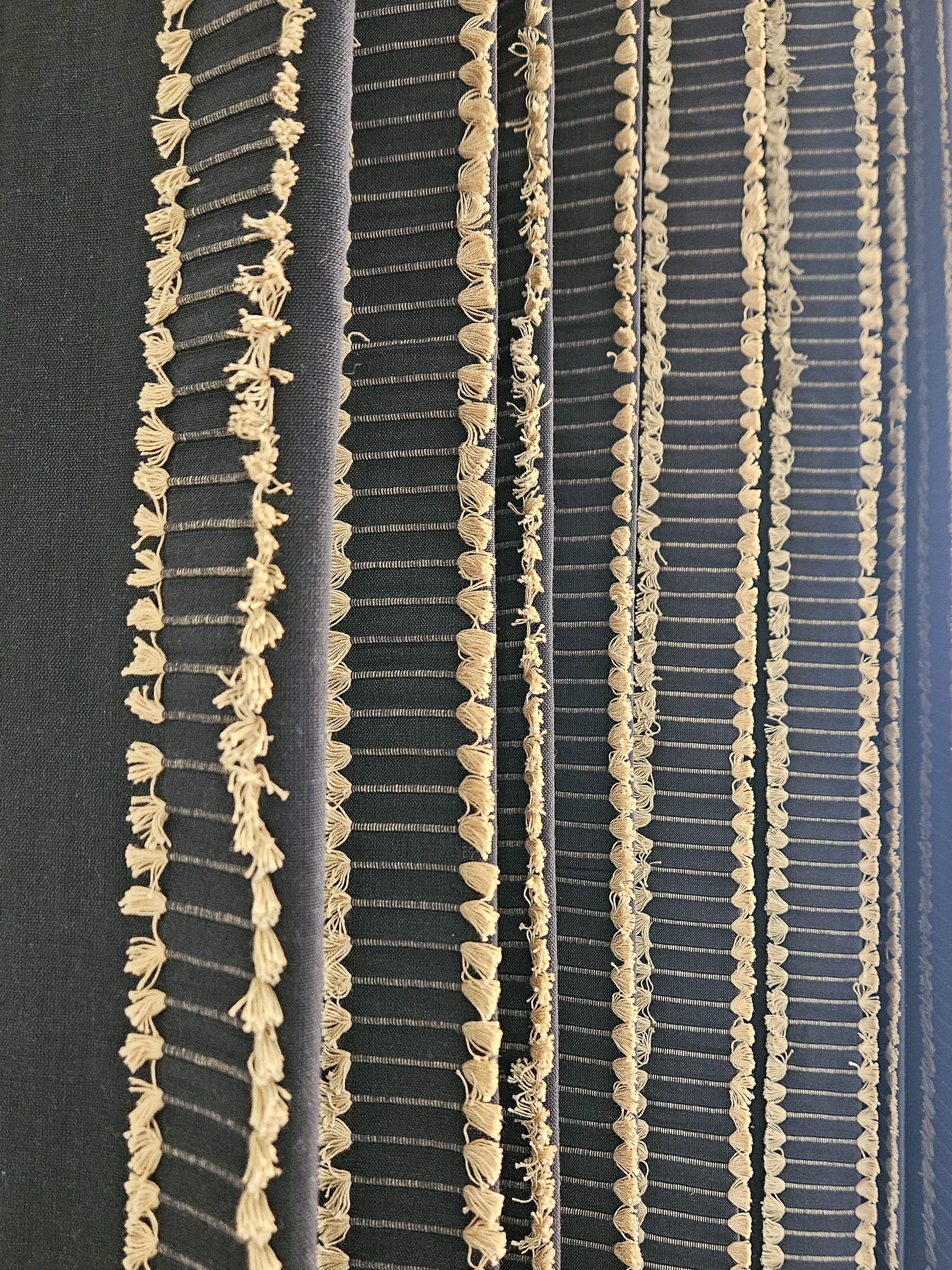 Rhythmic tassel trim and vertical line work add a bespoke layer of texture to full length linen drapery.