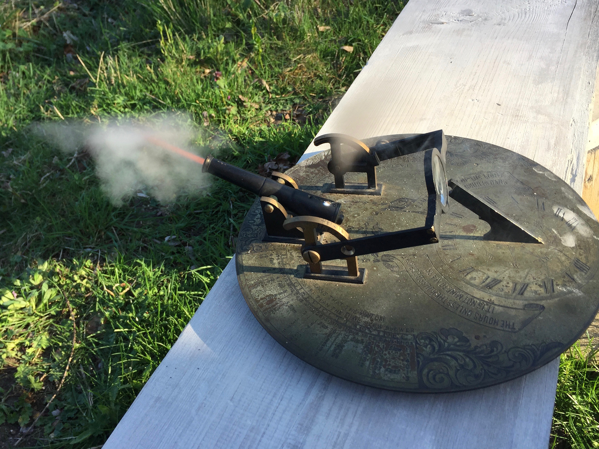 A Sundial Gun or Meridian Cannon. The Sundial would be oriented North/South, the lens would be adjusted according to the declination of the sun. The gun would fire automatically. However, in practical terms, the sundial would be watched until it reached noon, then the lens would be moved to focus the sun's beam onto the gun's touch pan. (This photo was taken in the afternoon!)