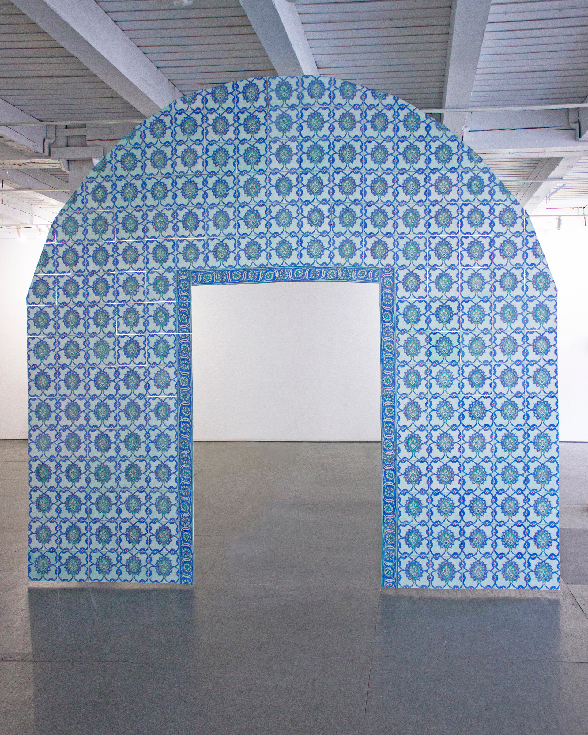 Front view of "Their Natural State," a sculpture recreation of an archway facade at King Davids Tomb in Jerusalem. The sculpture is made up of paper tiles created with vellum, hand drawn with marker, and strung together with fishing line. the final product is a ghost-like memorial. Each tile is painted with blue, turquoise, green and red floral patterns.