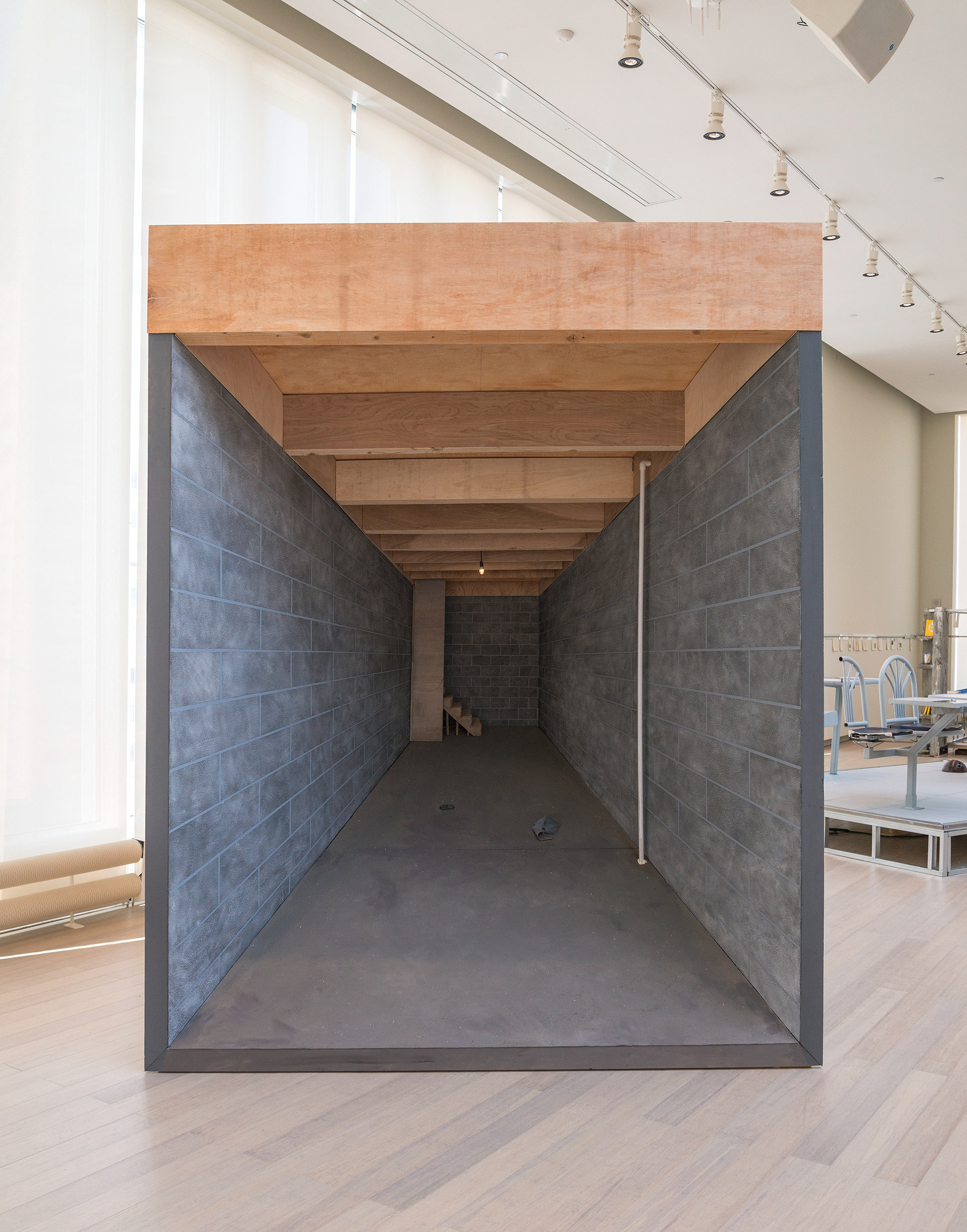 An image of "Silver Bullet Test Site" showing a direct frontal view of the sculpture. viewed directly, one sees a point perspective model of a basement that moves from the actual scale of the viewer to miniature scale, creating a false sense of dimension.