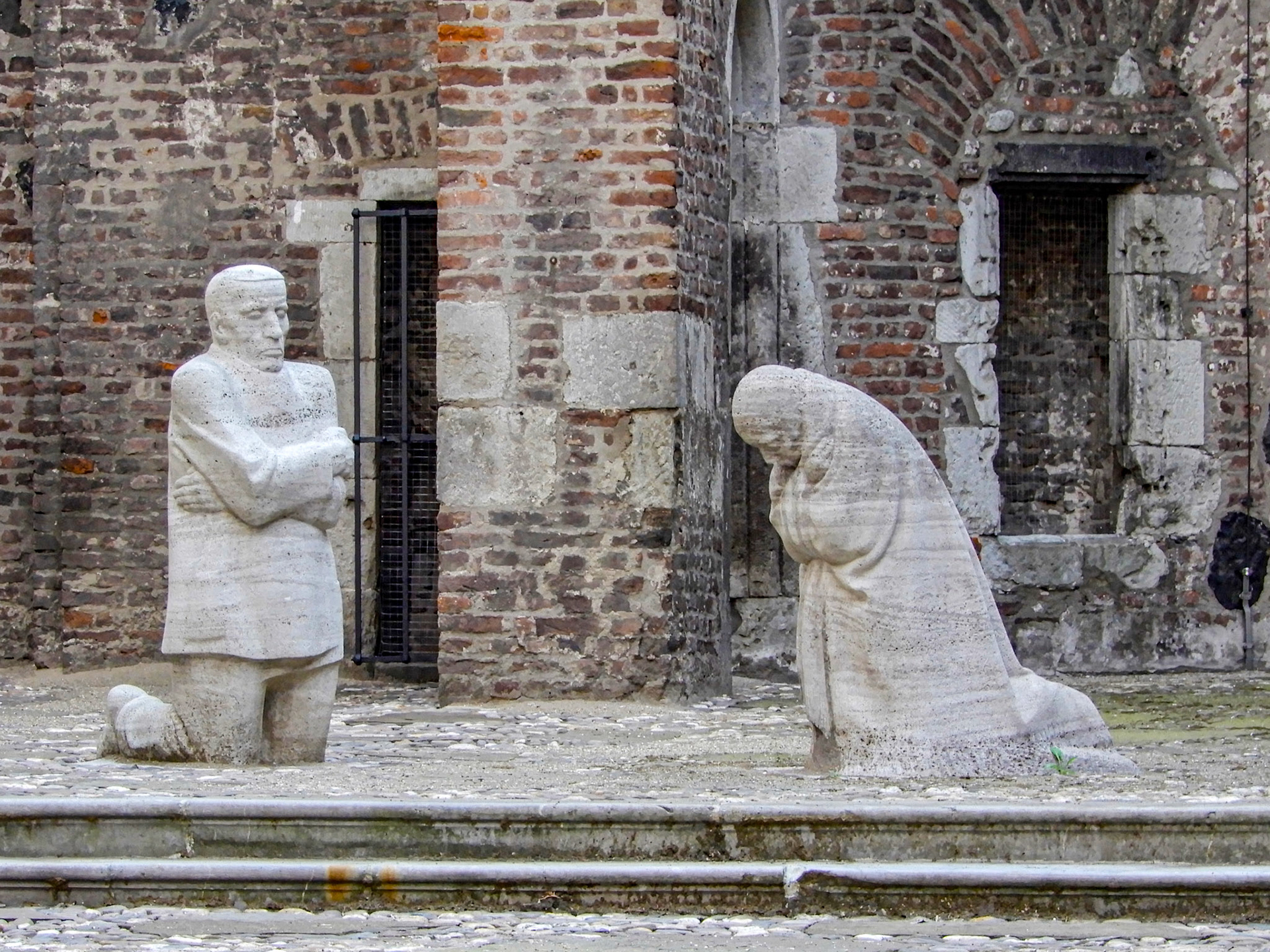 Statue "Mourning Parents" of Käthe Kollwitz, a memorial for died prisoners-of-war, in the ruins of Old St. Alban, a medieval Romanesque church & monuments heavily damaged in World War II.