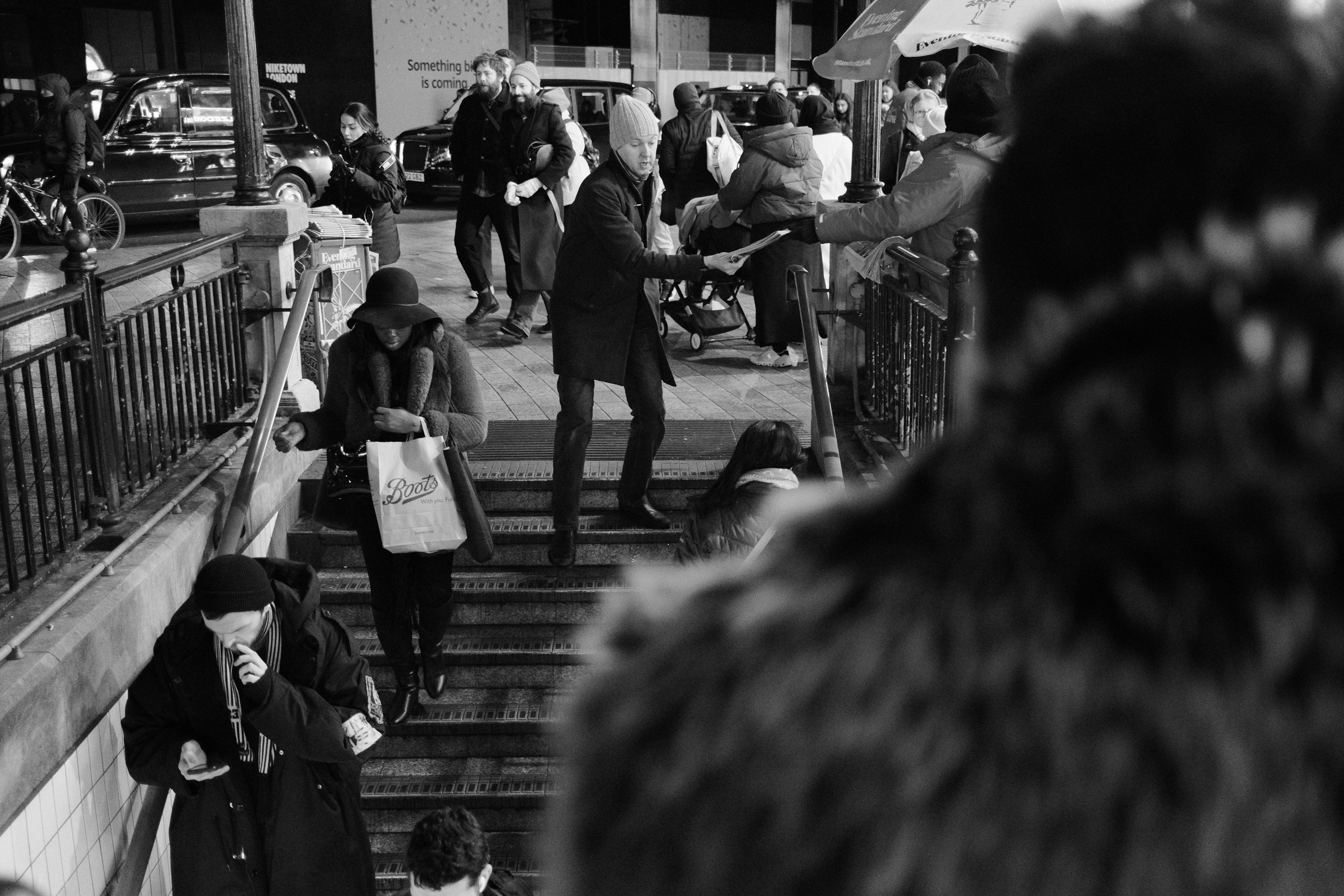 A man reaching for an Evening Standard newspaper. London, England 2024.
