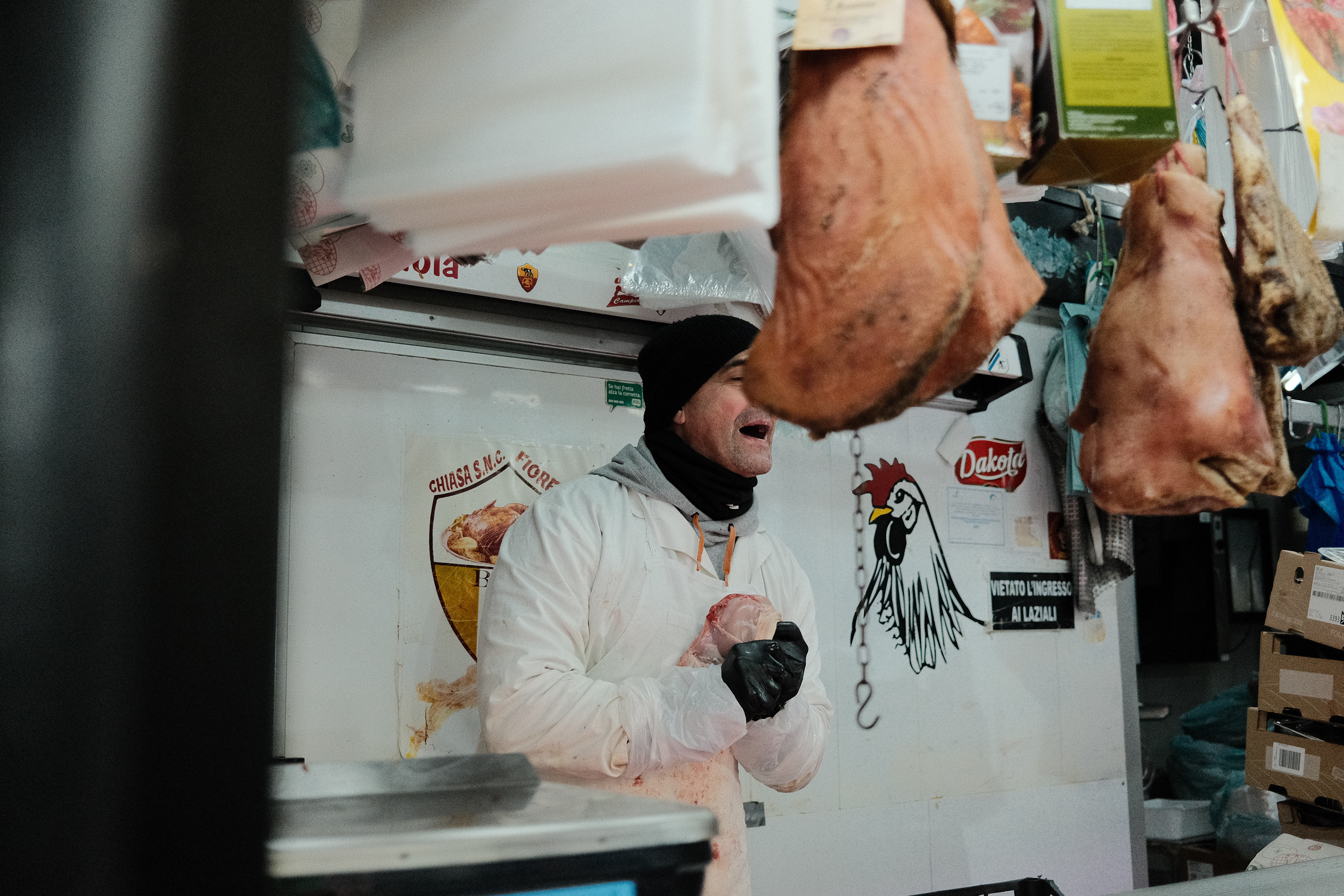 A butcher conversing intensely with a customer. Rome, Italy 2024.