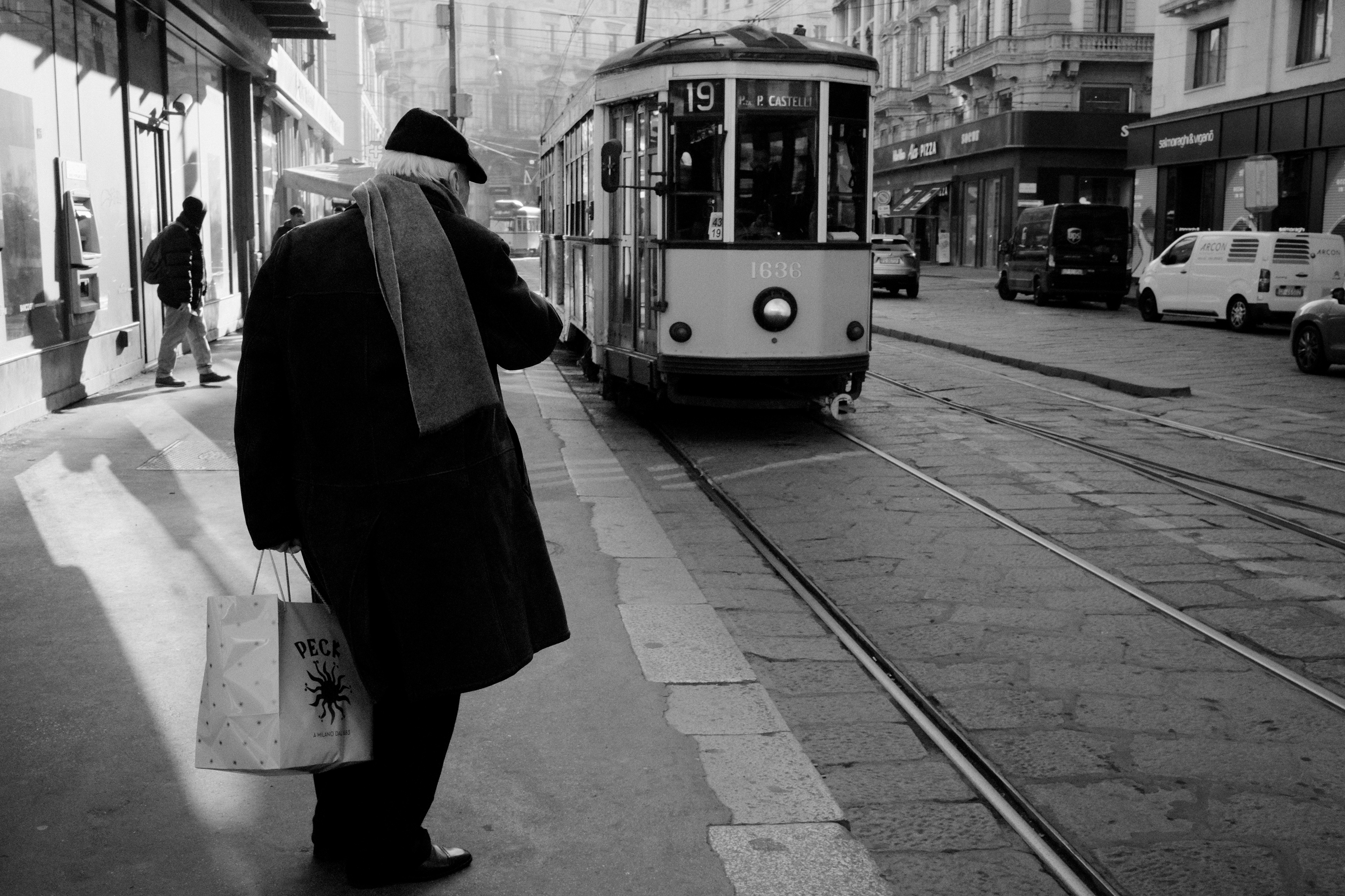 Man at a streetcar stop. Milan, Italy 2025.