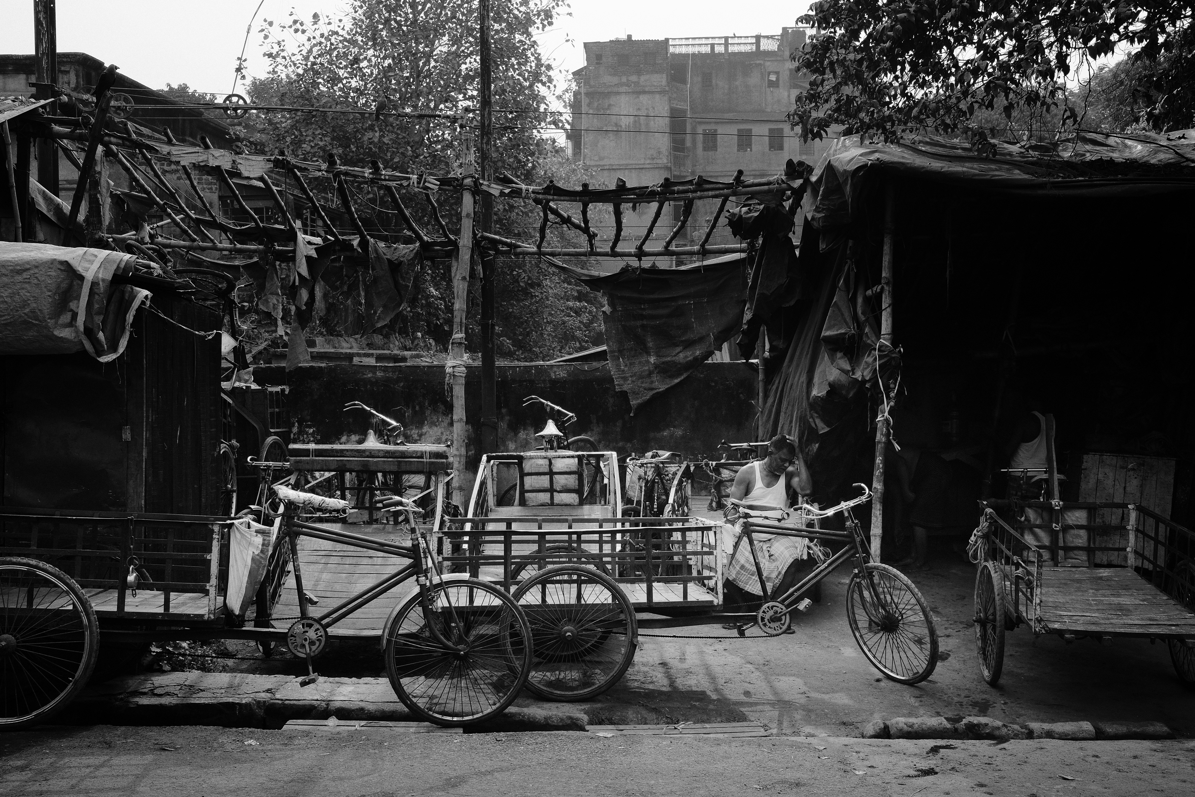 A lonely man sits between a handful of cycle rickshaws. Calcutta, India 2024.