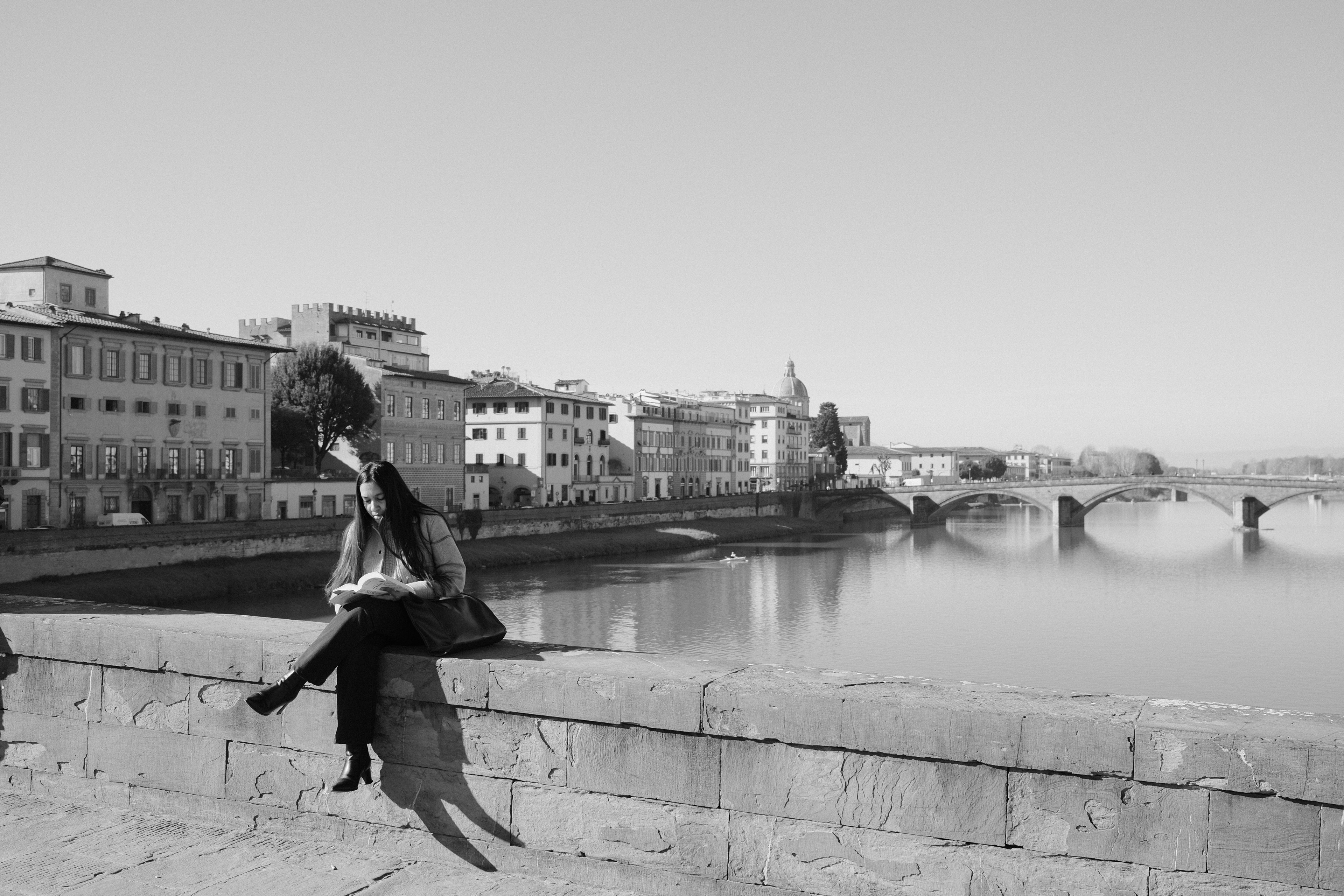 A lady reading above the Arno river. Florence, Italy 2024.