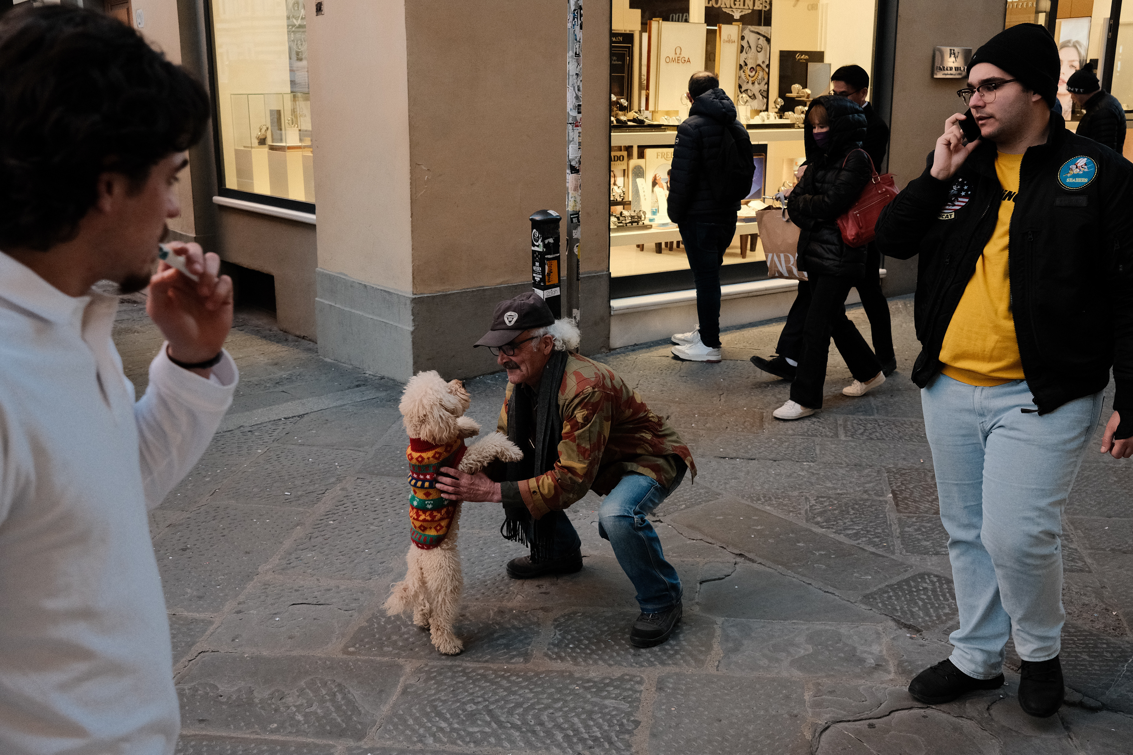 Man picking up his dog. Florence, Italy 2024.