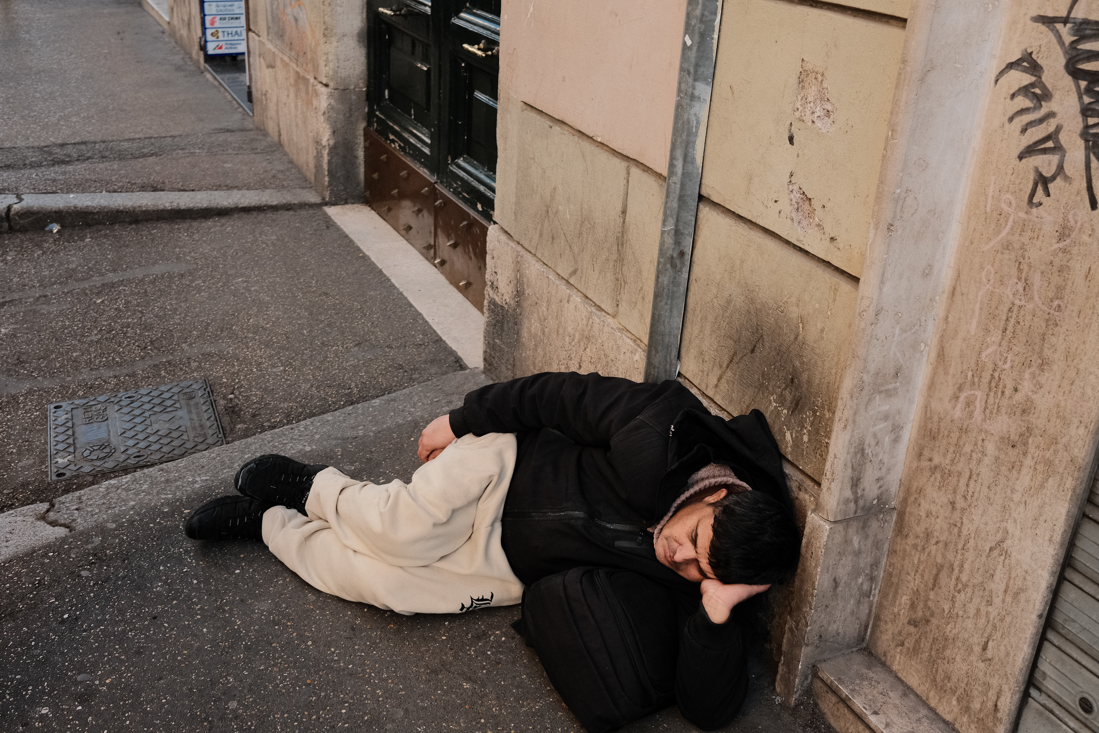 Man taking a nap on a sidewalk. Rome, Italy 2024.