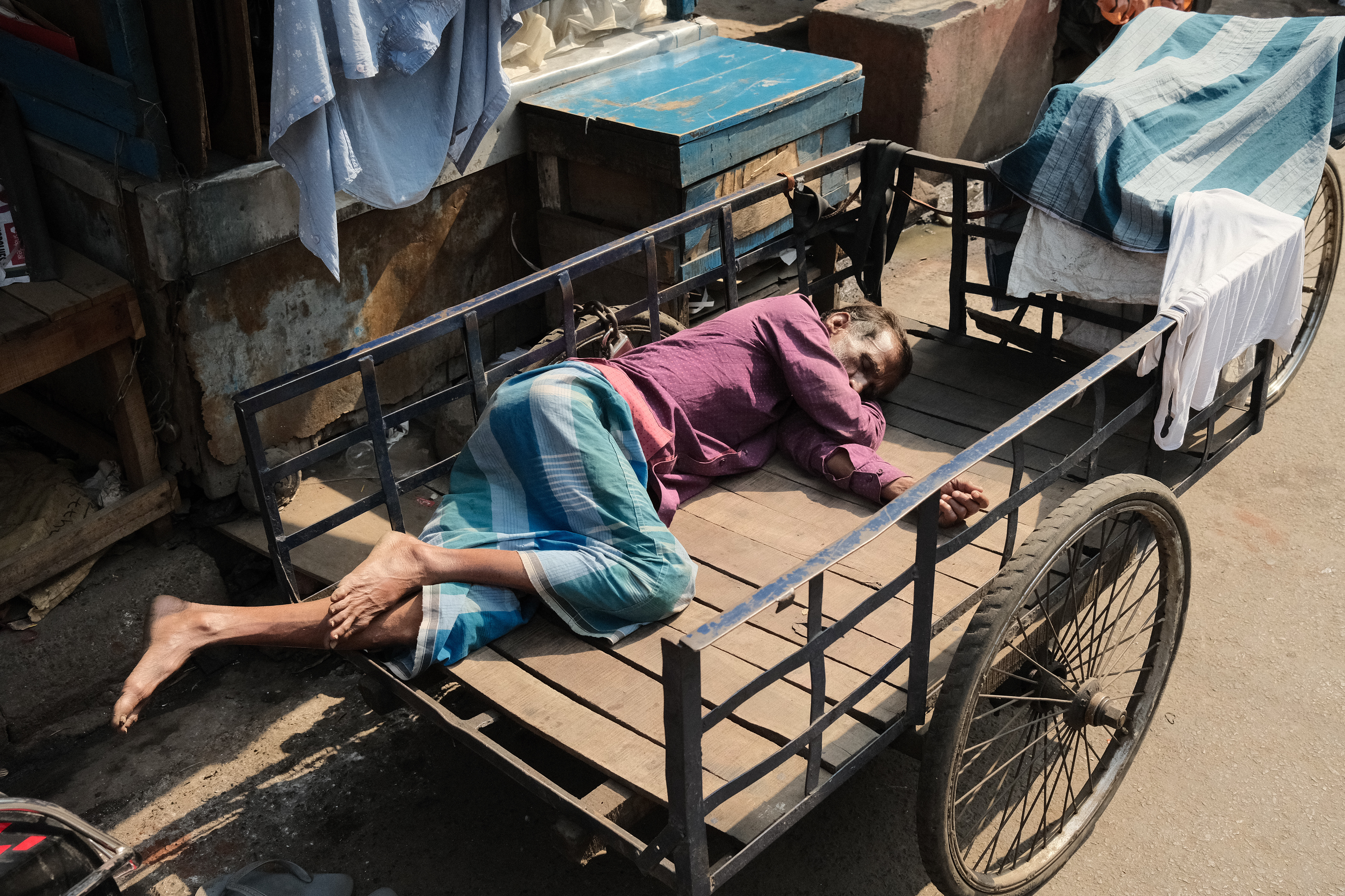 A man sleeping in a cycle rickshaw. Calcutta, India 2024.
