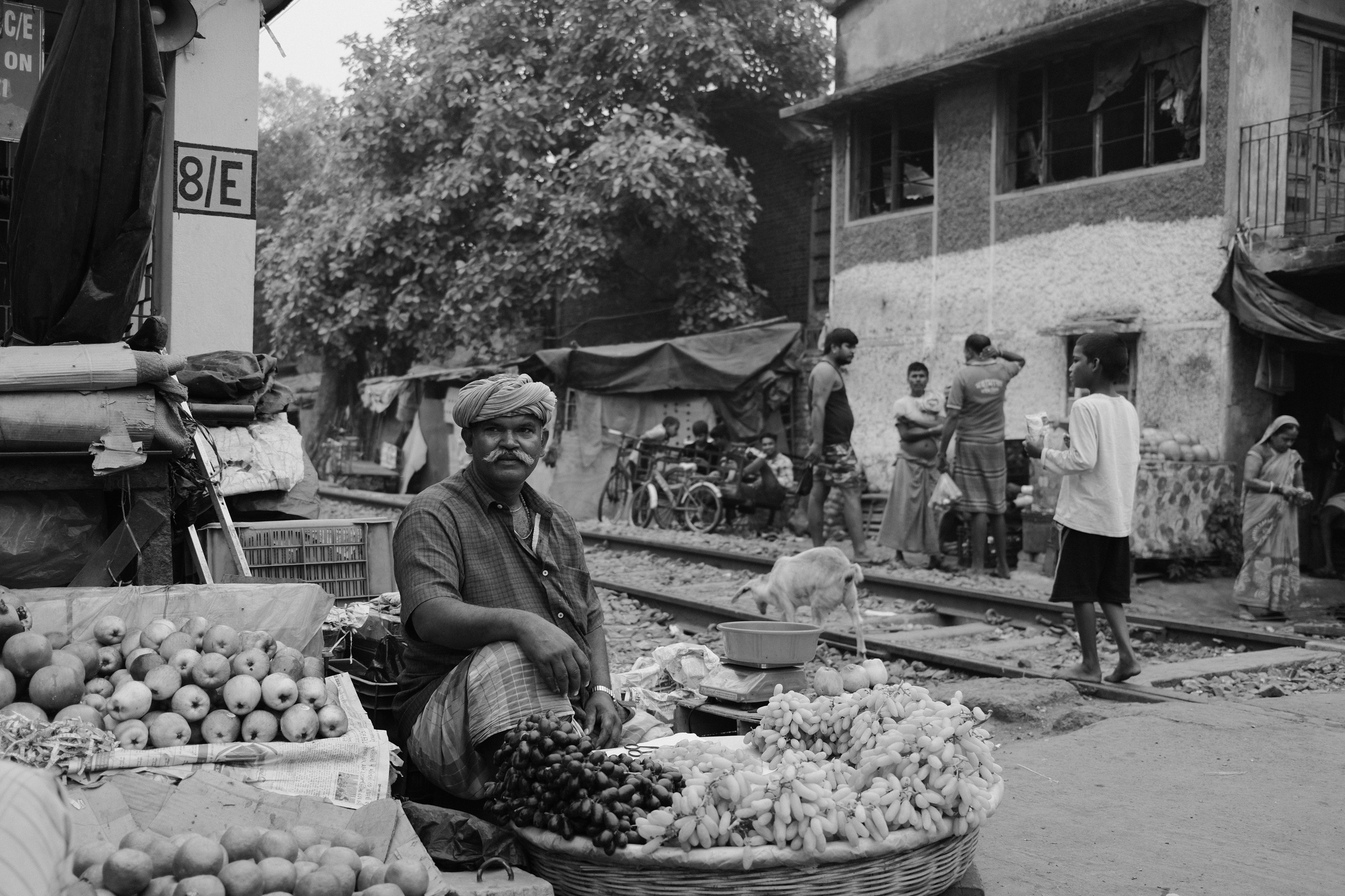 A man selling grapes at a railway crossing. Calcutta, India 2024.