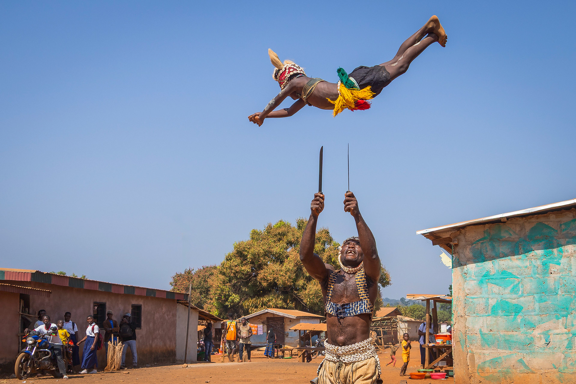 A member of the Gueré tribe in Ivory Coast juggles with huge daggers and a child